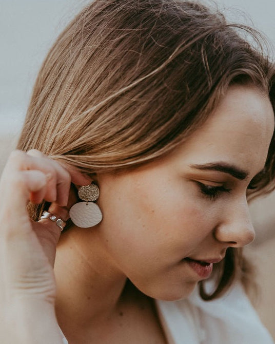 Bride wears gold sparkly cream statement pebble blob earrings.