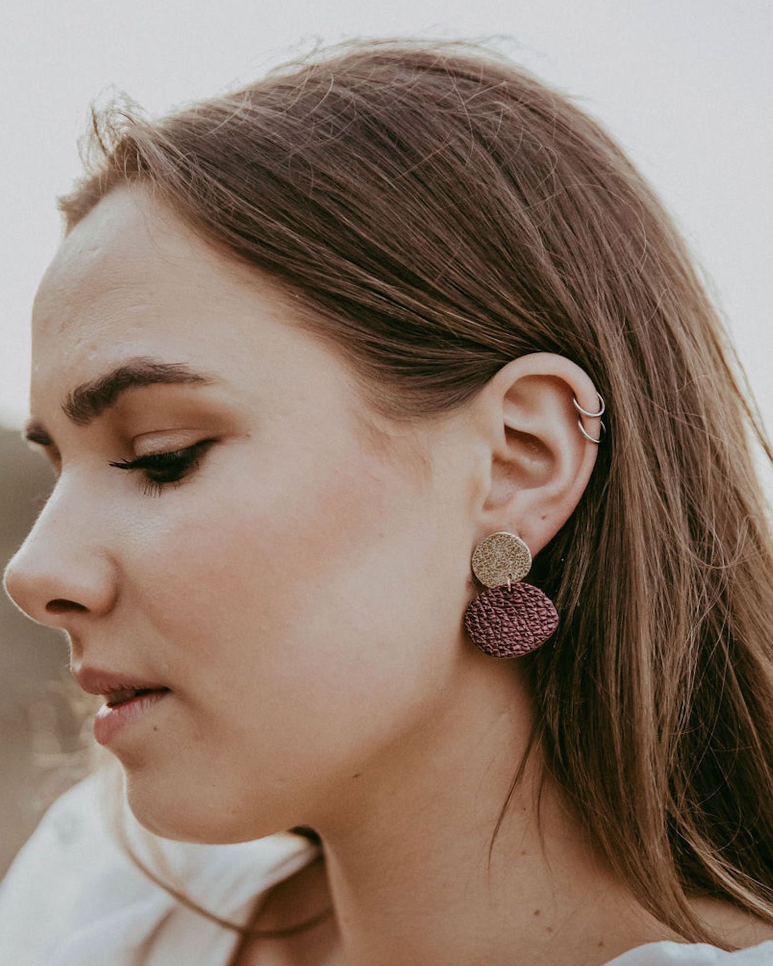 Bride wears gold and burgundy red metallic earrings.
