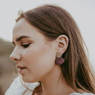 Bride wears gold and burgundy red metallic earrings.