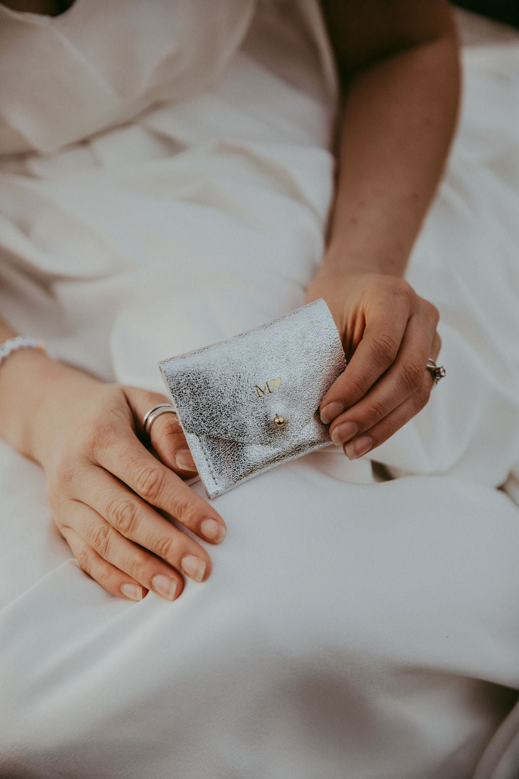 Bride holding silver leather wedding ring pouch