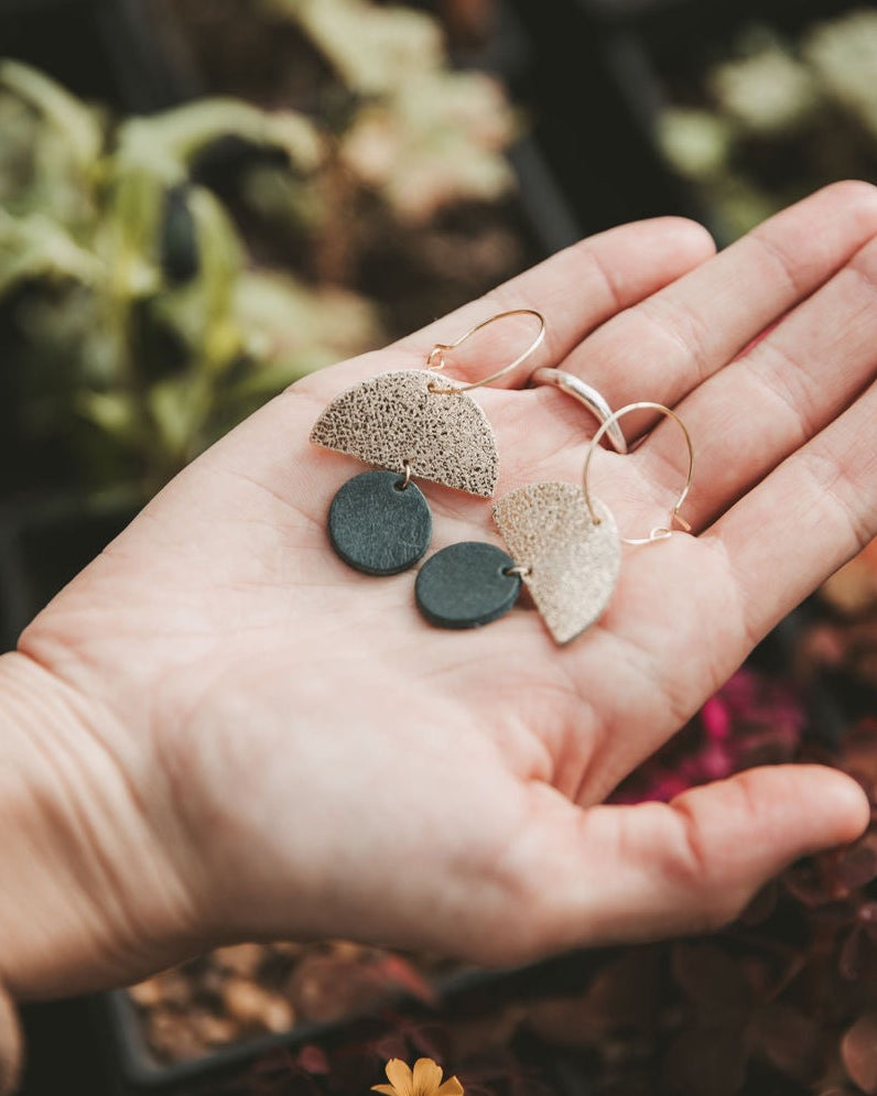 The sunrise hoop earrings in forest green within a palm