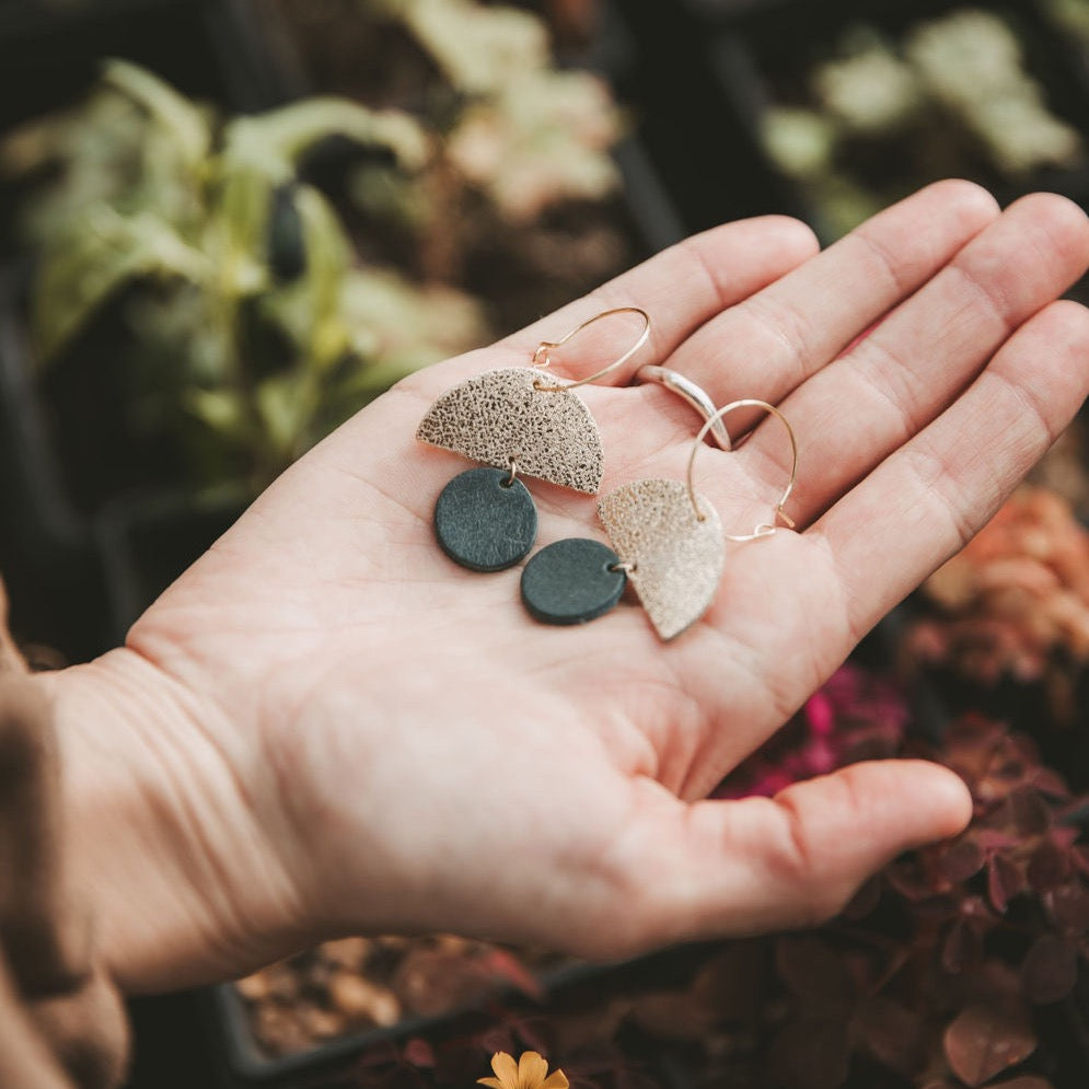 The sunrise hoop earrings in forest green within a palm