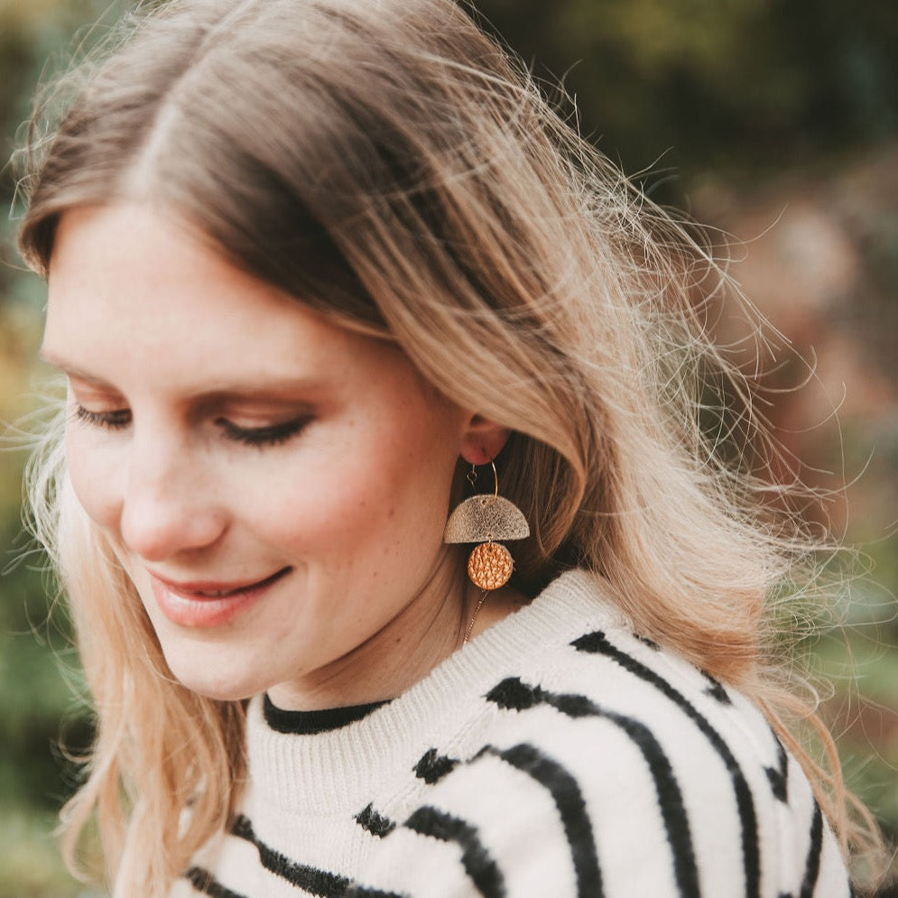 Model wearing the leather sunrise hoop earrings in metallic copper