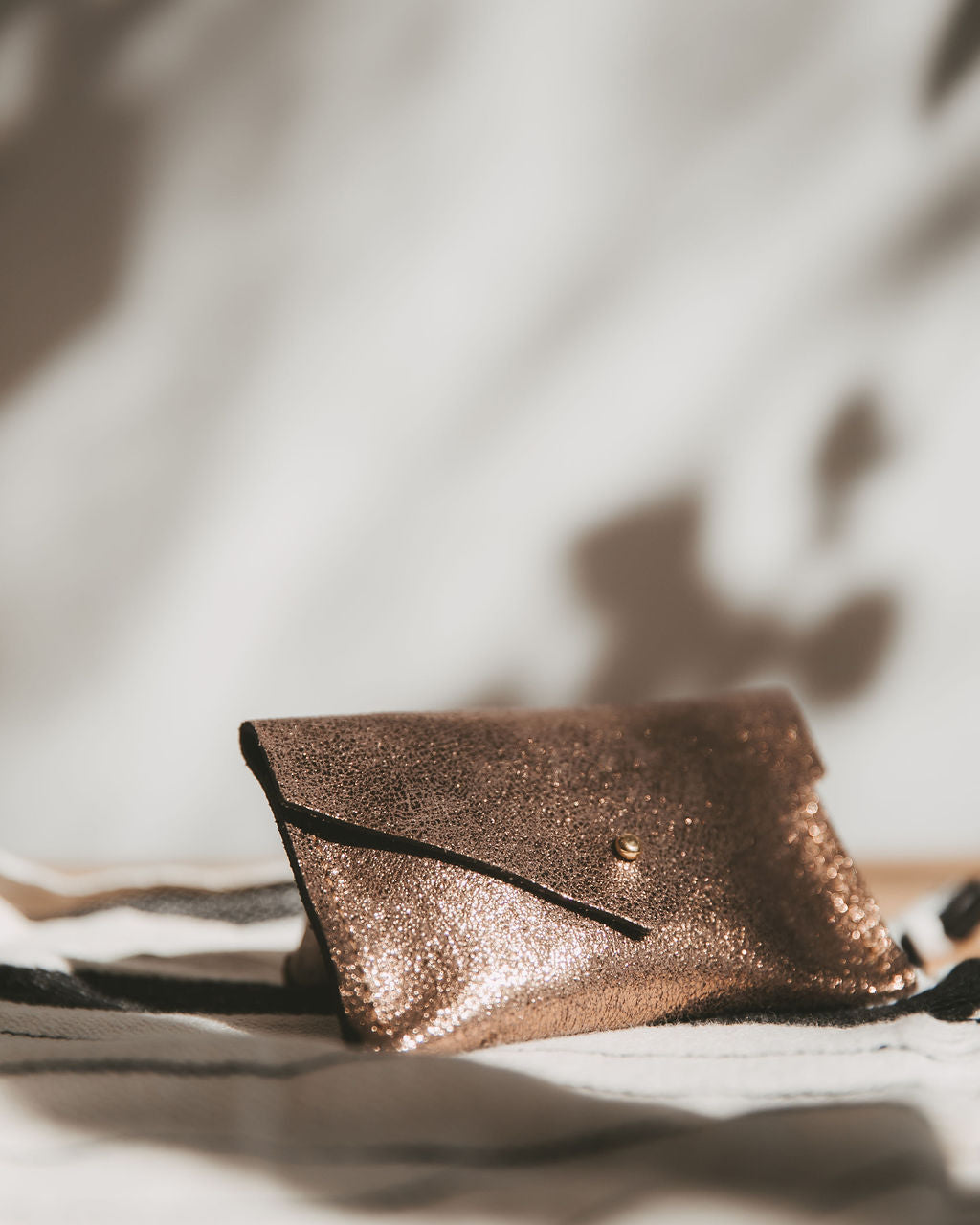 Bronze leather envelope wallet on a textured surface with soft lighting