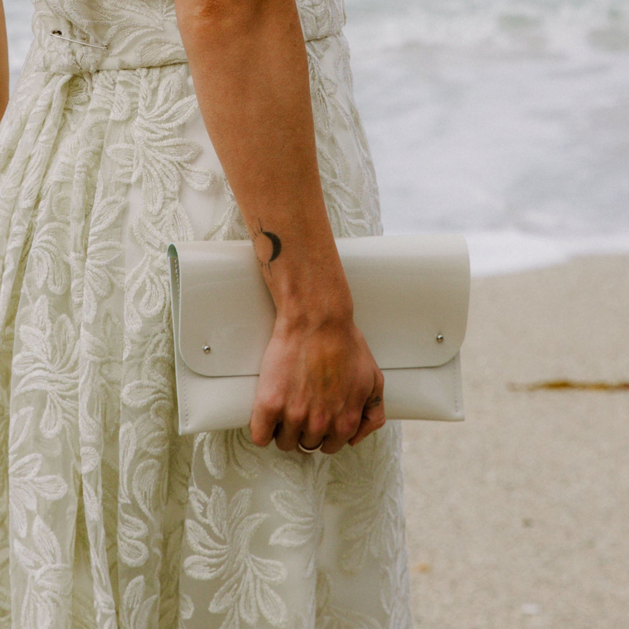 Bridal Pearl White Clutch Bag worn by bride on a beach on her wedding day.