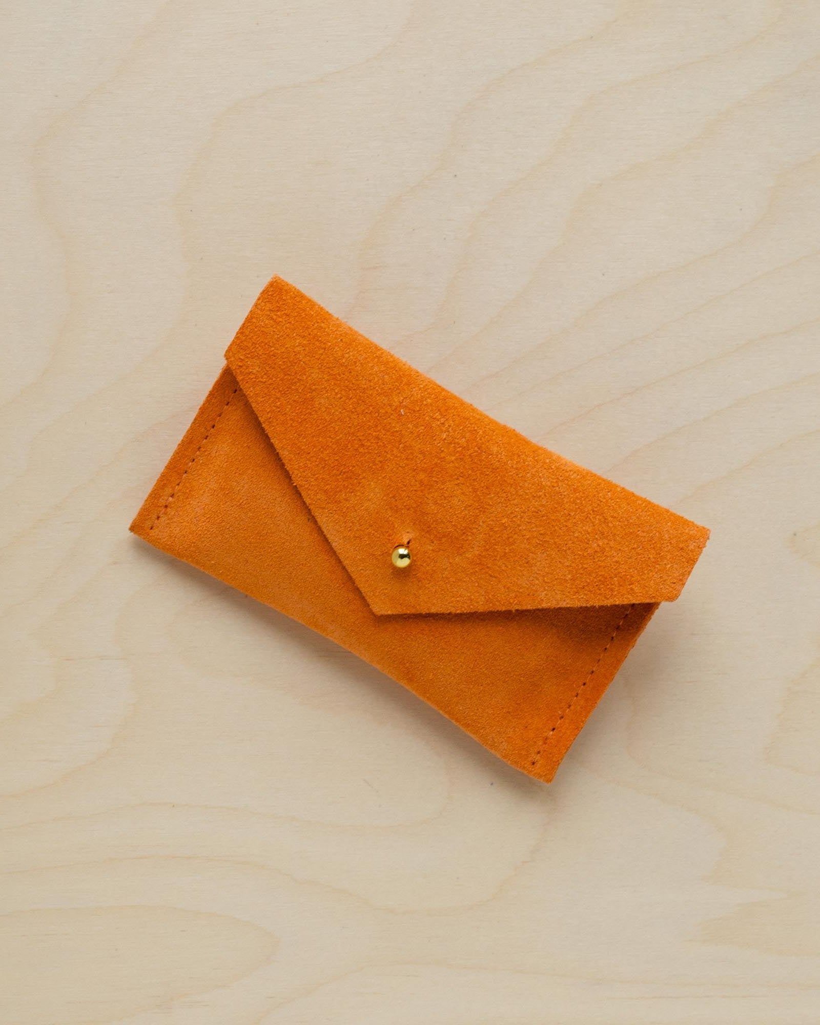 A suede Small Notions Pouch in orange. Complete with a stud for secure closing.