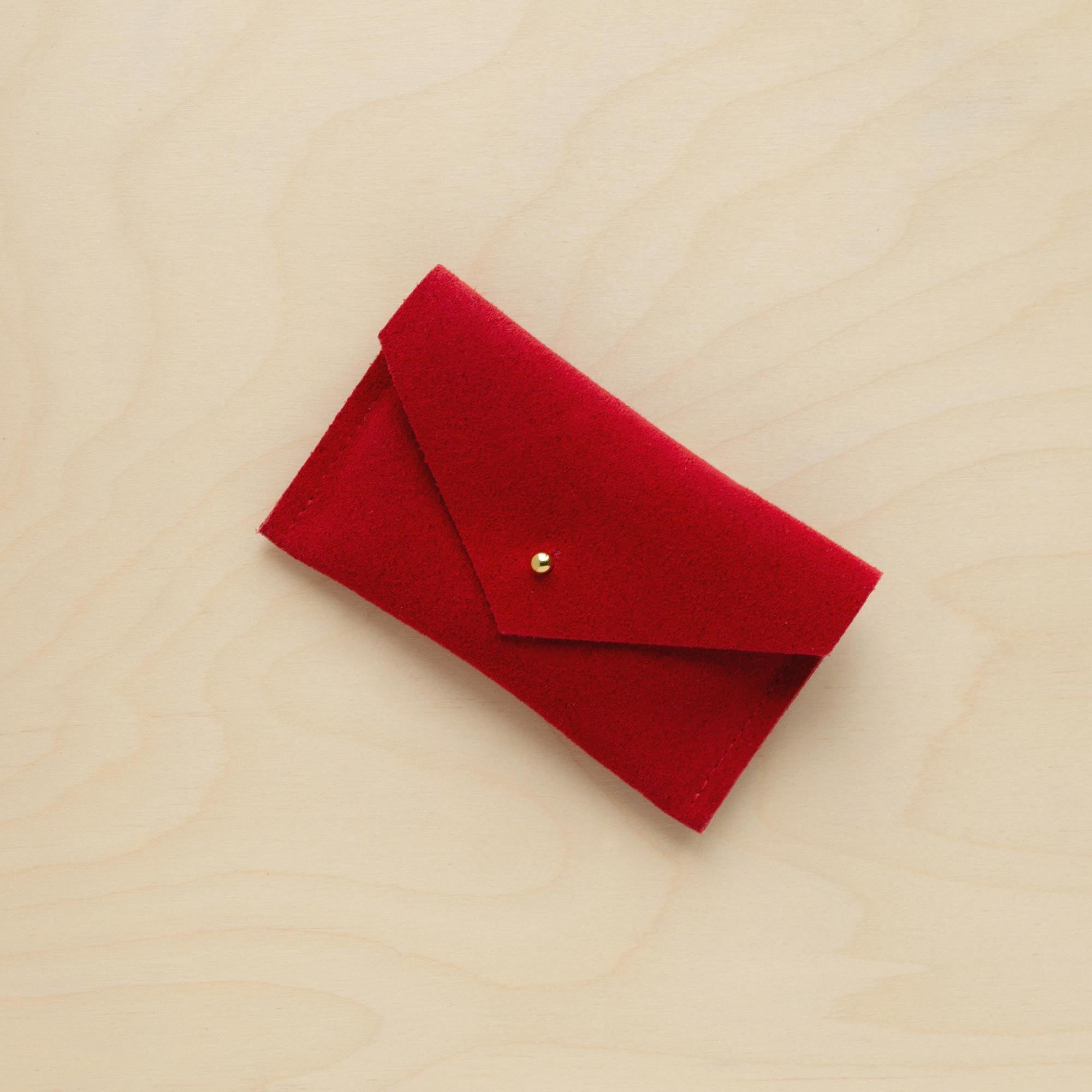 A suede Small Notions Pouch in Crimson Red. Complete with a stud for secure closing.