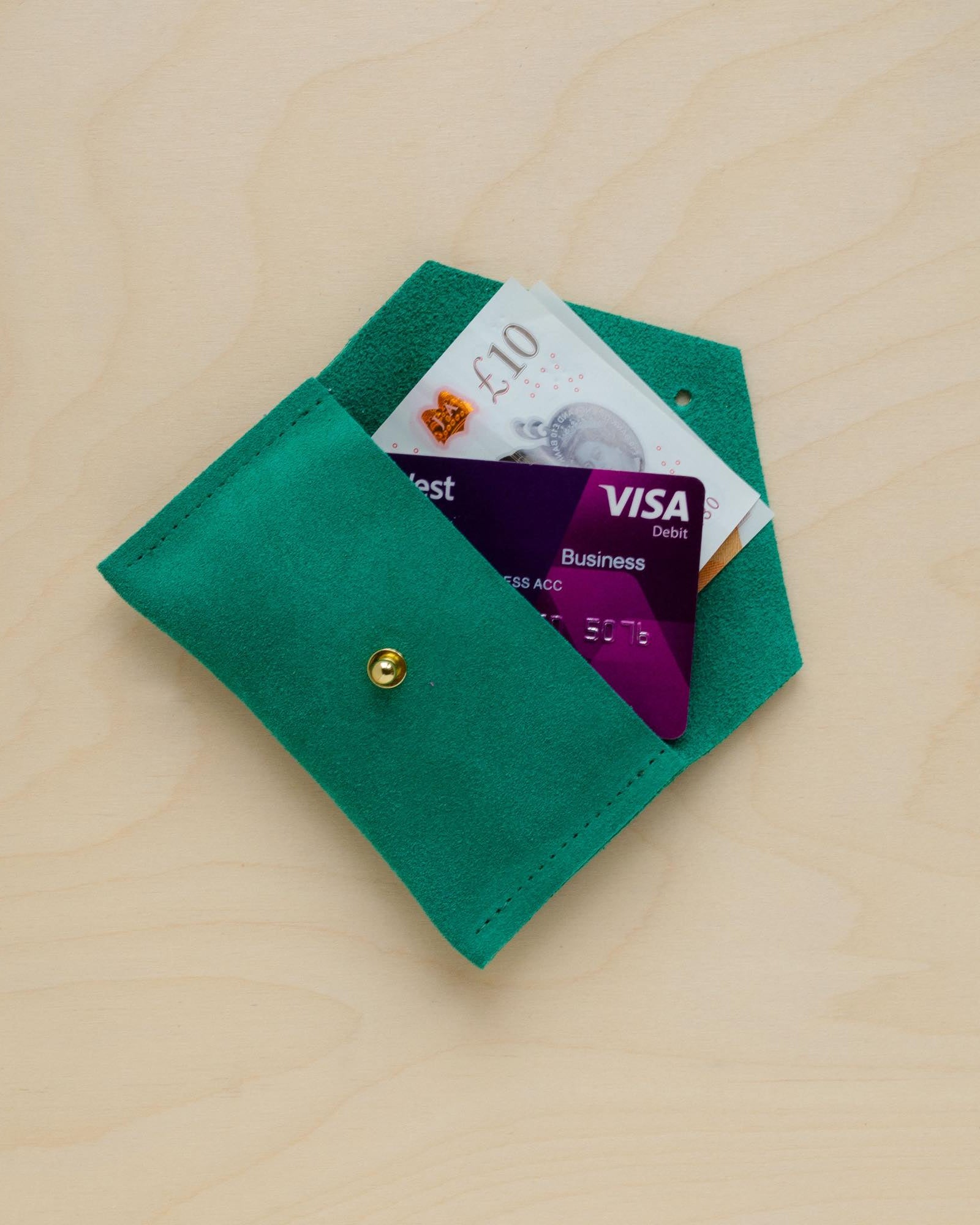 Bright Green suede purse with money and credit cards in it.