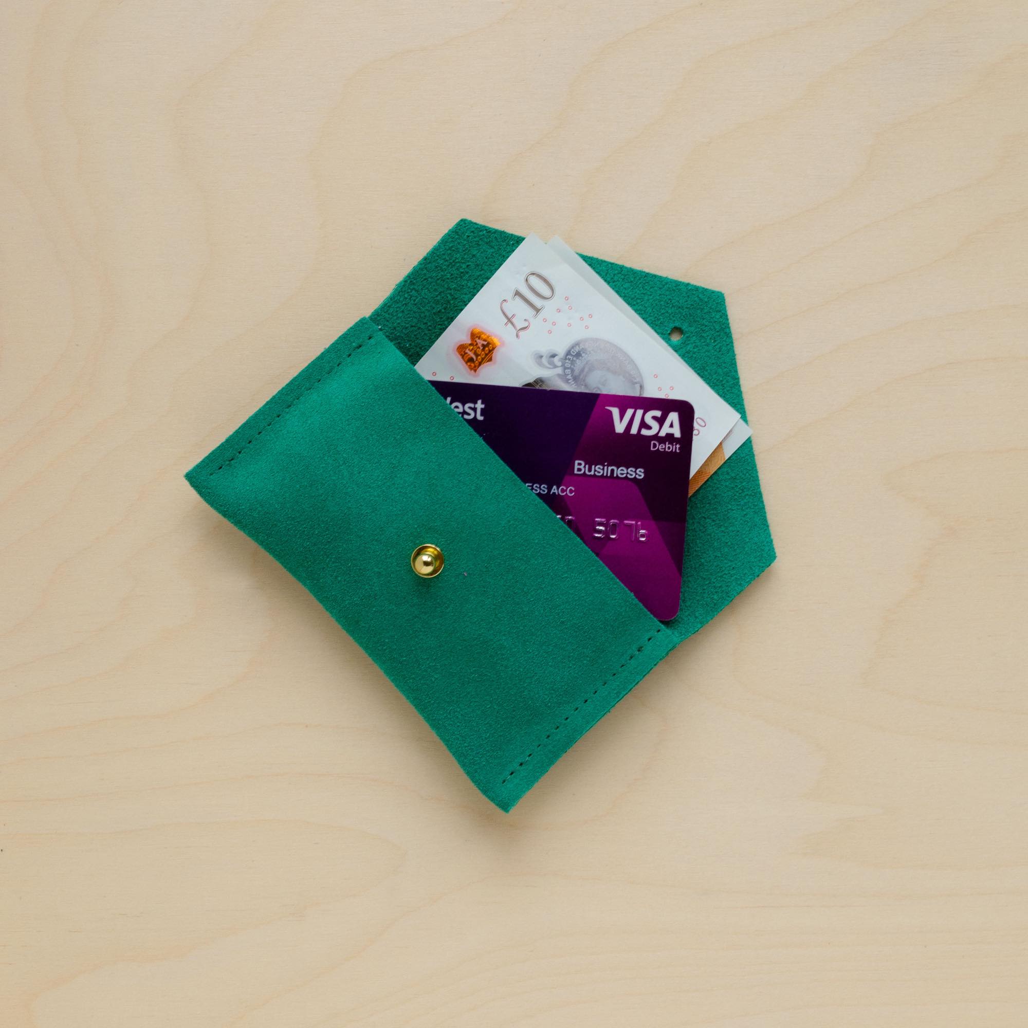 Bright Green suede purse with money and credit cards in it.