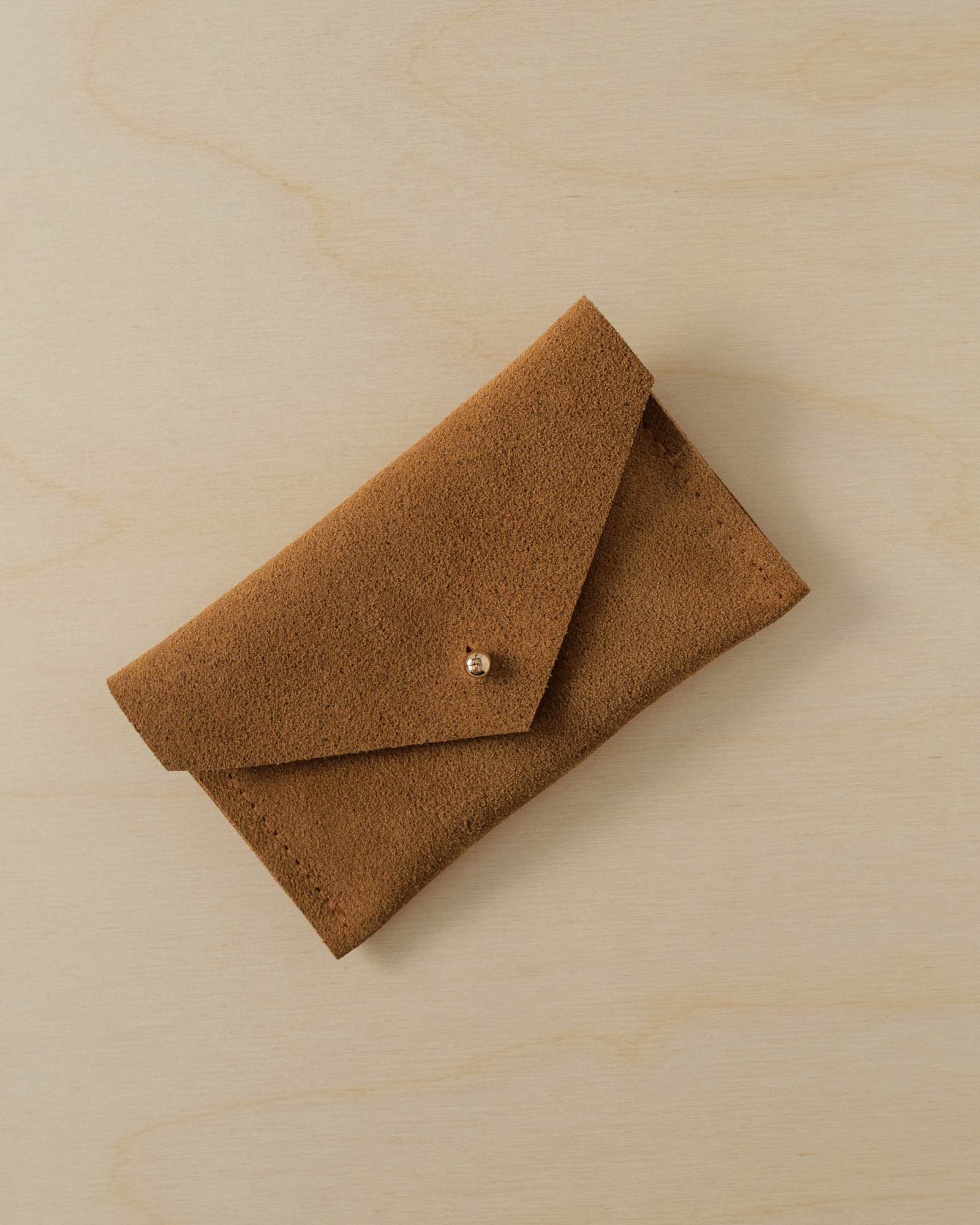 A suede Small Notions Pouch in Tan brown. Complete with a stud for secure closing.