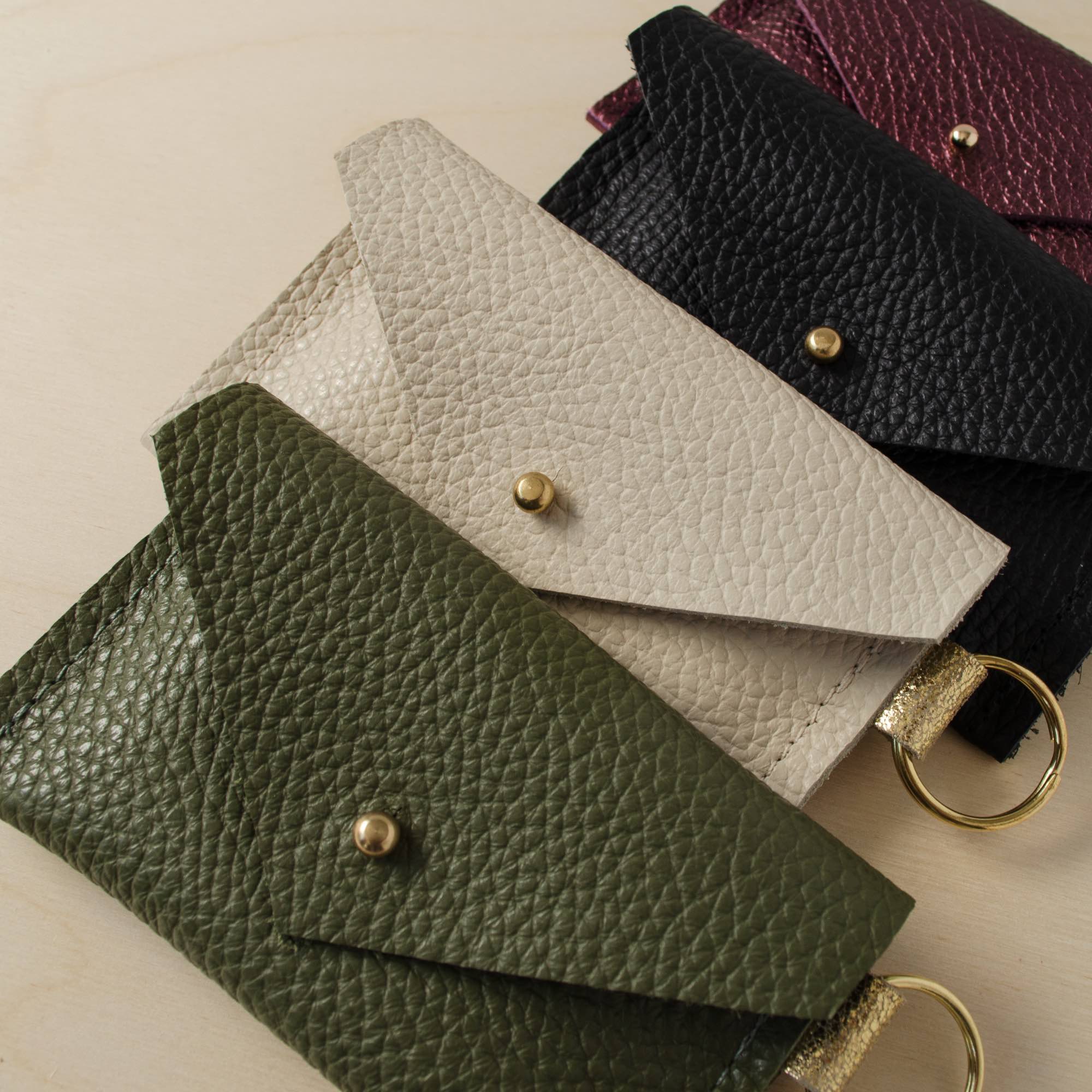 Four leather keyring card holders in, Metallic Berry, Black, Cream and Olive Green.