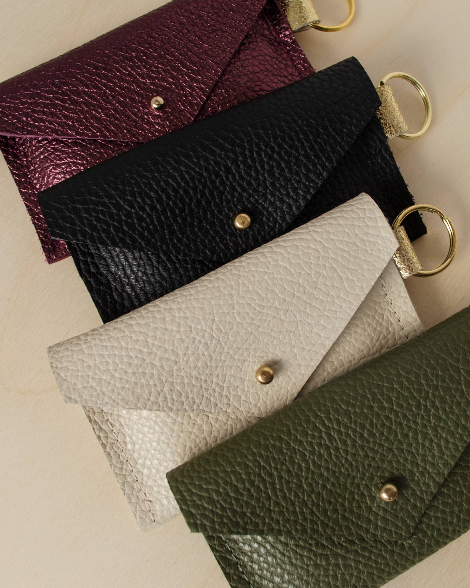 Four leather keyring card holders in, Metallic Berry, Black, Cream and Olive.