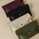 Four leather keyring card holders in, Metallic Berry, Black, Cream and Olive.
