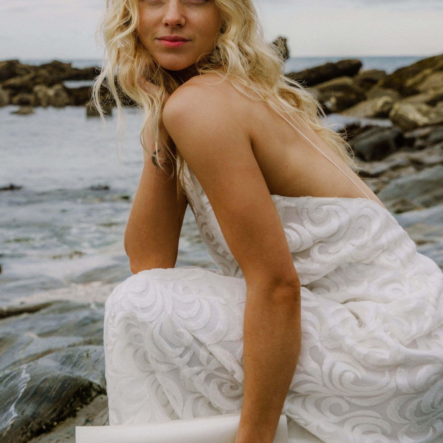 Maxi Bridal Clutch Bag in a pearl, ivory, off-white colour, worn by bride on her wedding day at a beach.