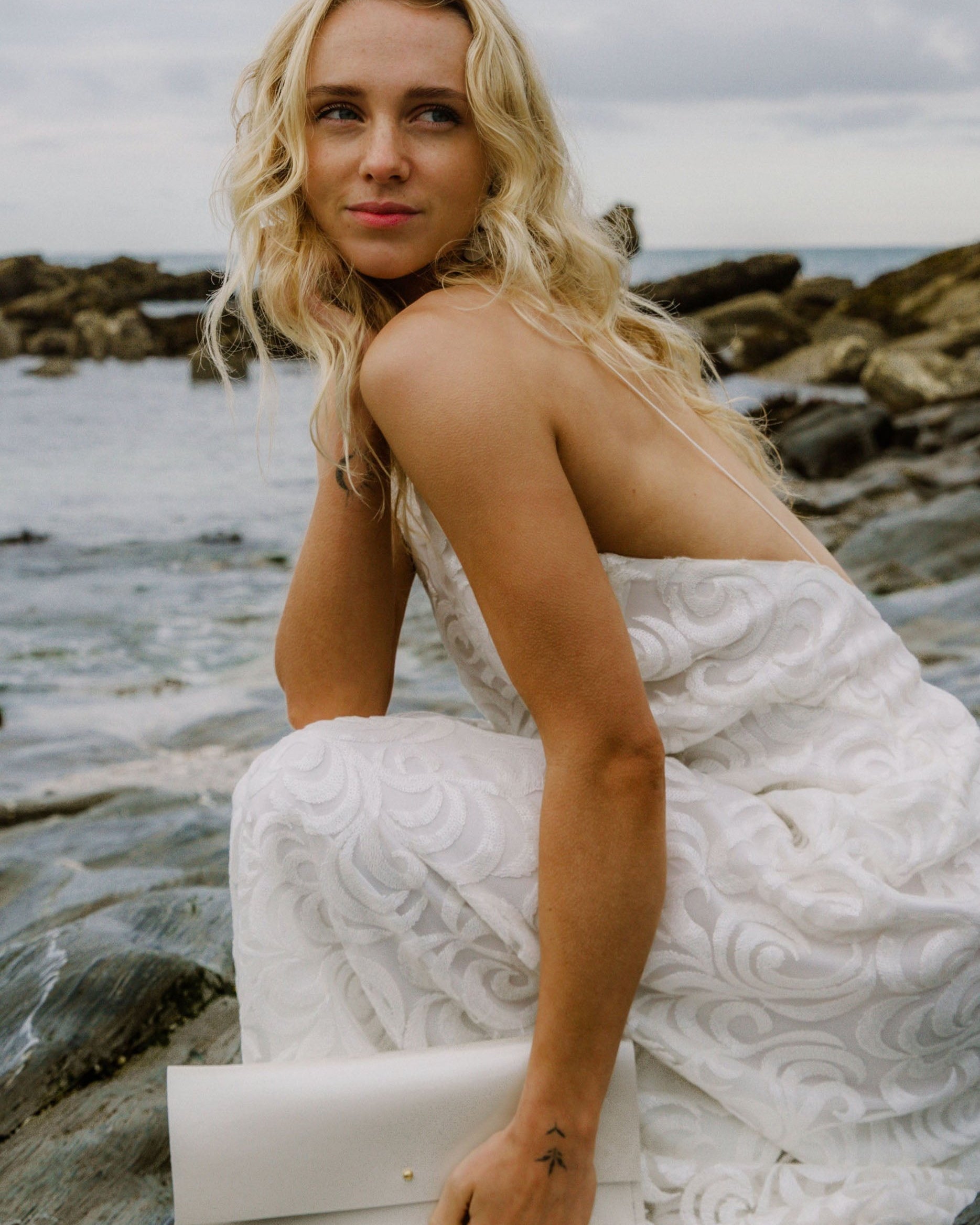 Maxi Bridal Clutch Bag in a pearl, ivory, off-white colour, worn by bride on her wedding day at a beach.