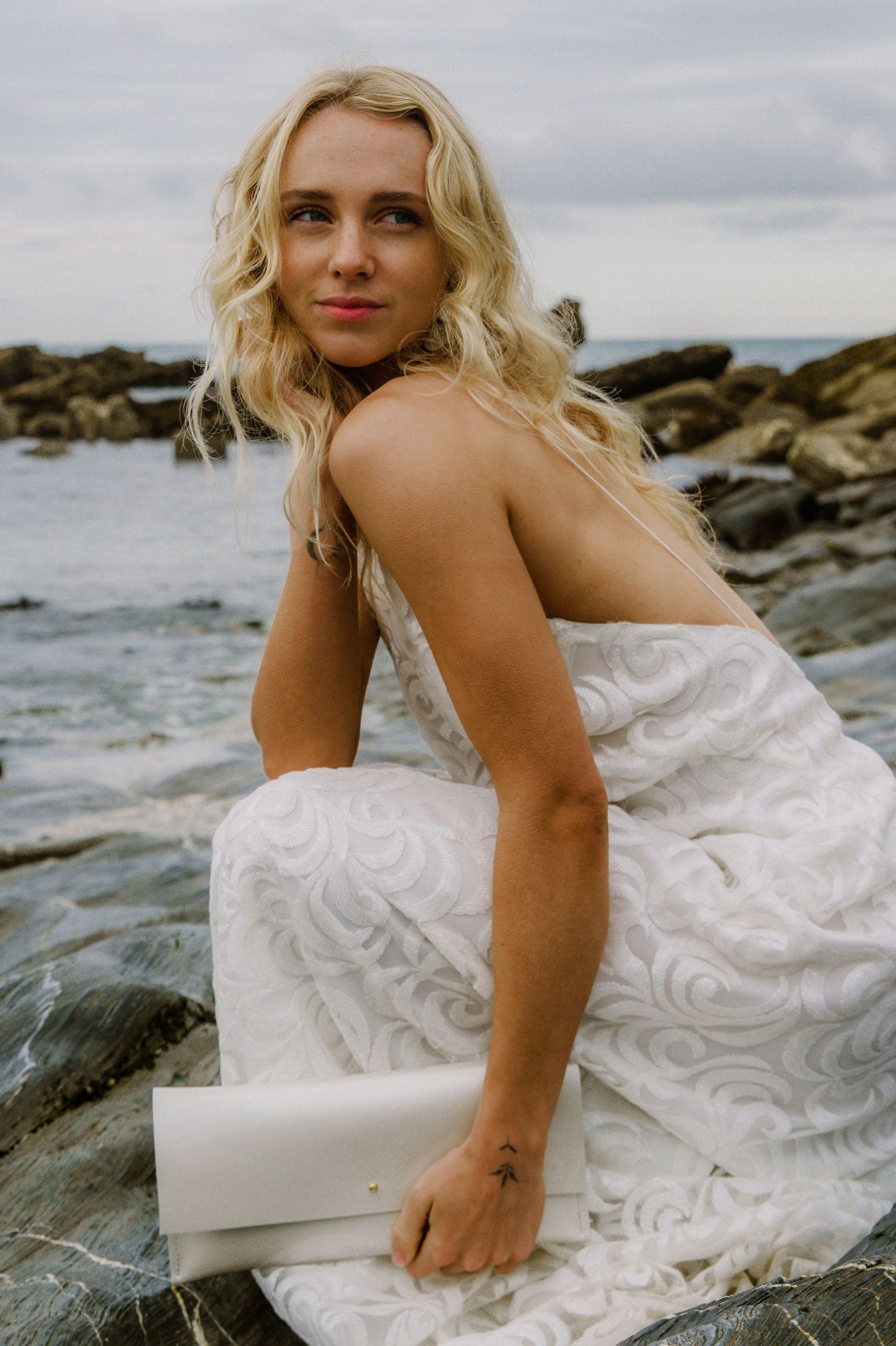 Maxi Bridal Clutch Bag in a pearl, ivory, off-white colour, worn by bride on her wedding day at a beach.