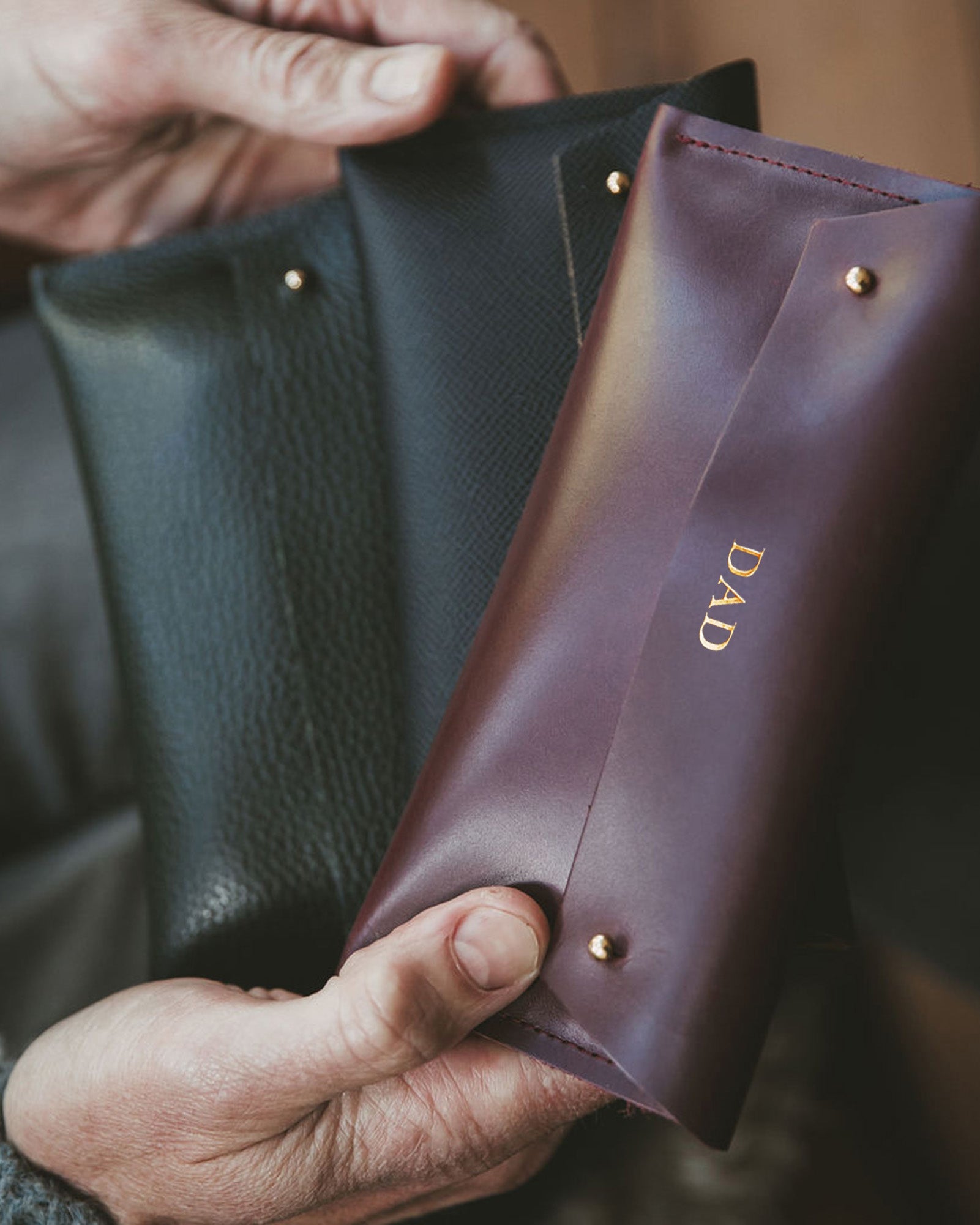 Man holds brown leather glasses case which is personalised with the word DAD.