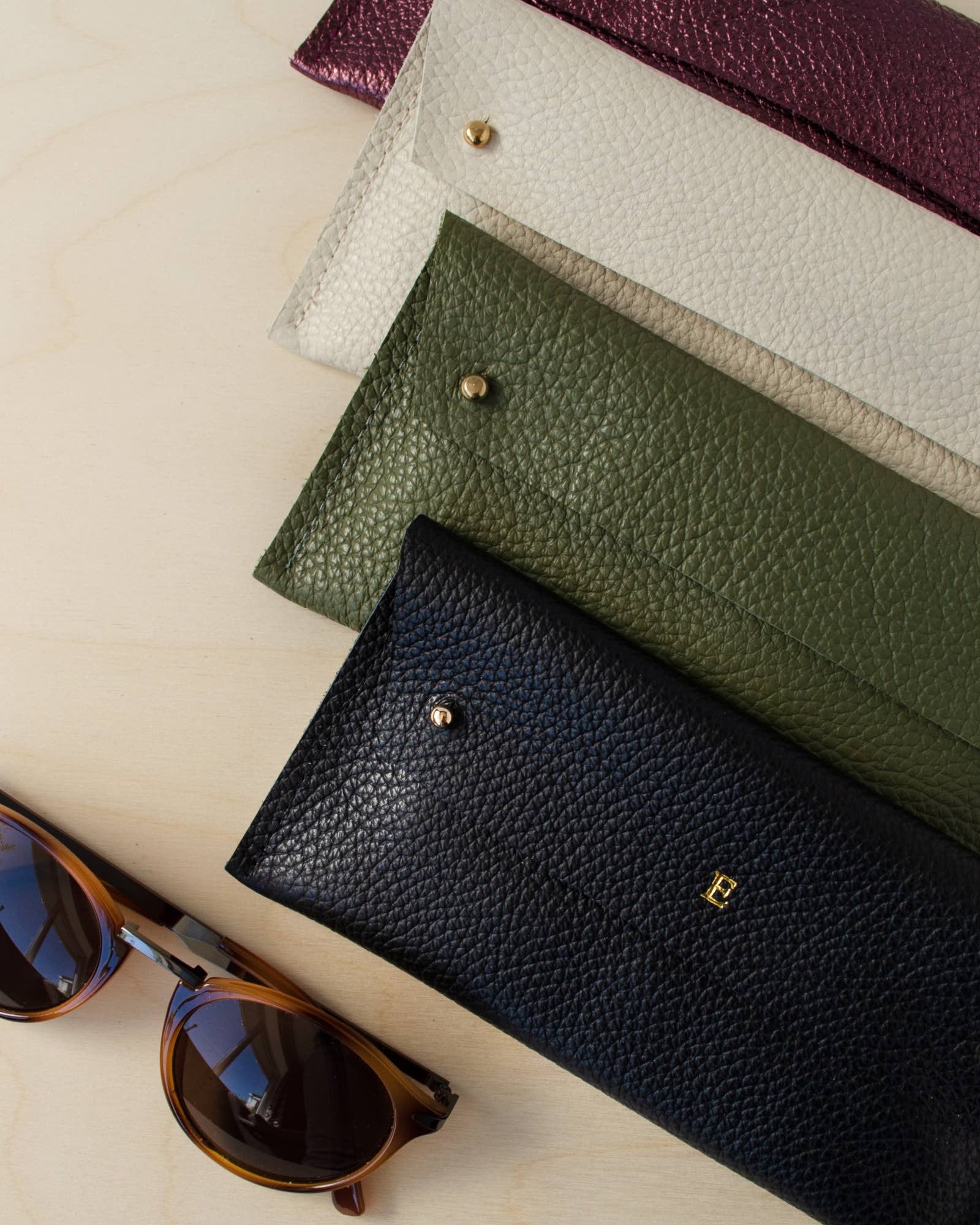 Four double stud glasses case in leather in black, olive green, cream and metallic berry.