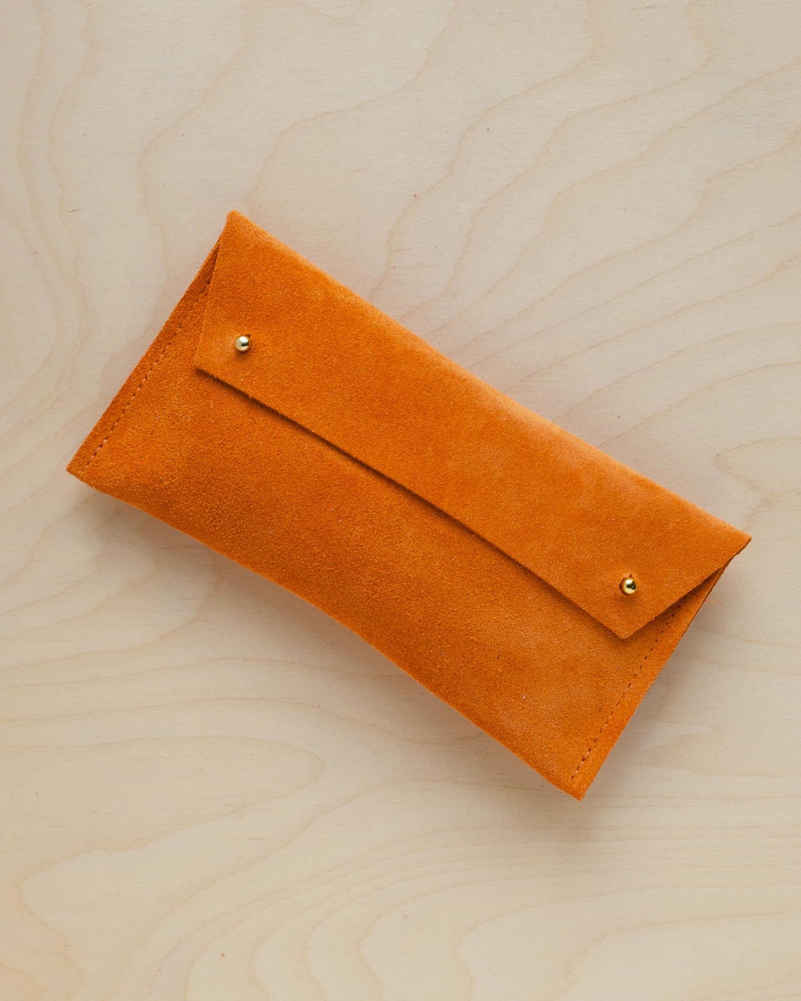 The suede pen case in orange. Featuring a double stud.