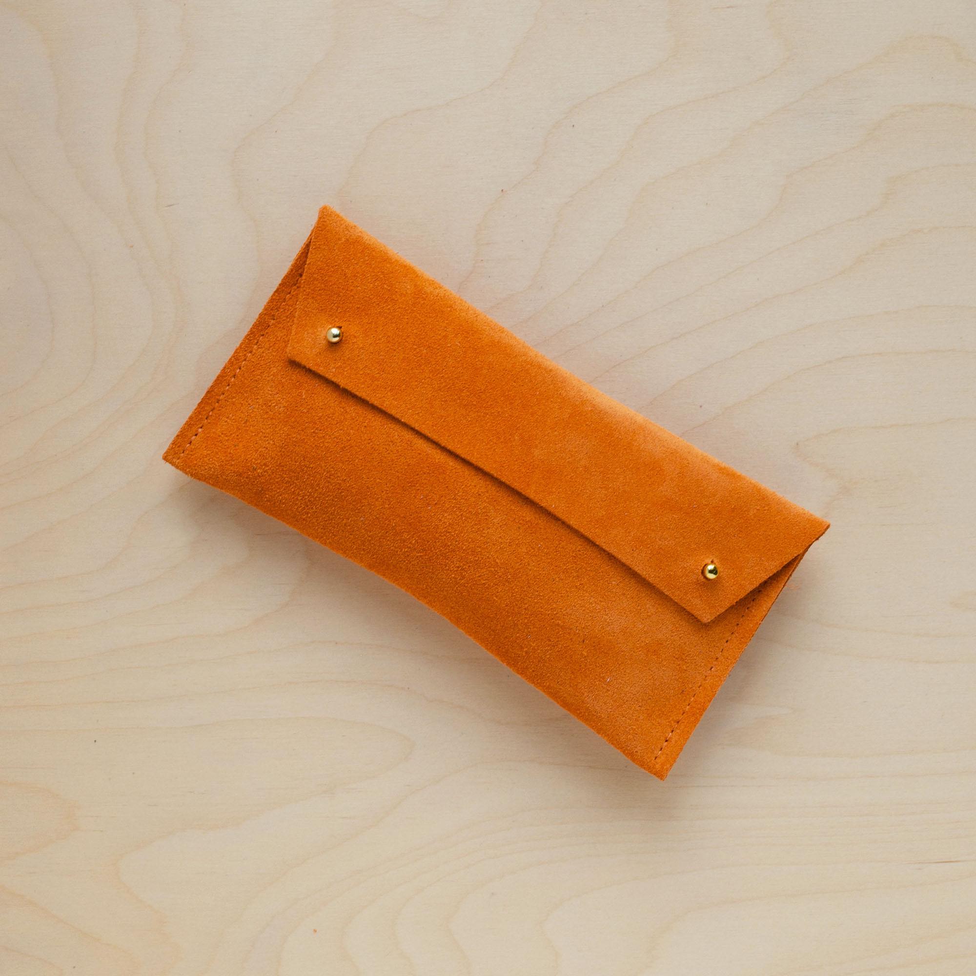 The suede pen case in orange. Featuring a double stud.