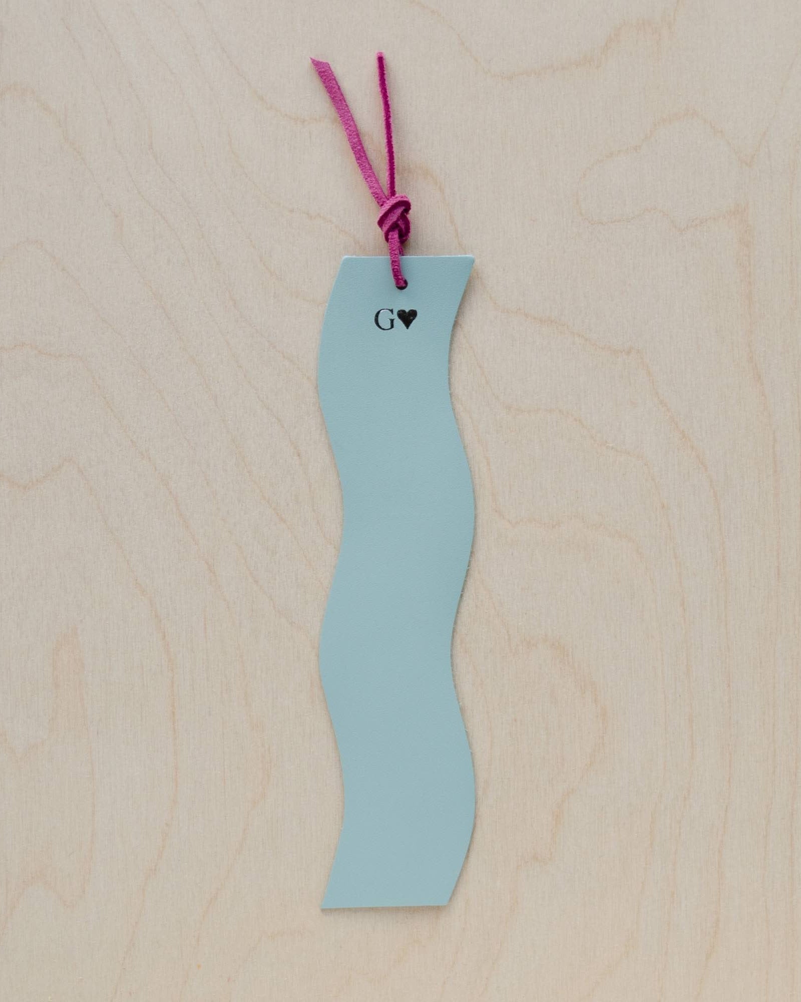 Pale blue leather bookmark on a wooden background.