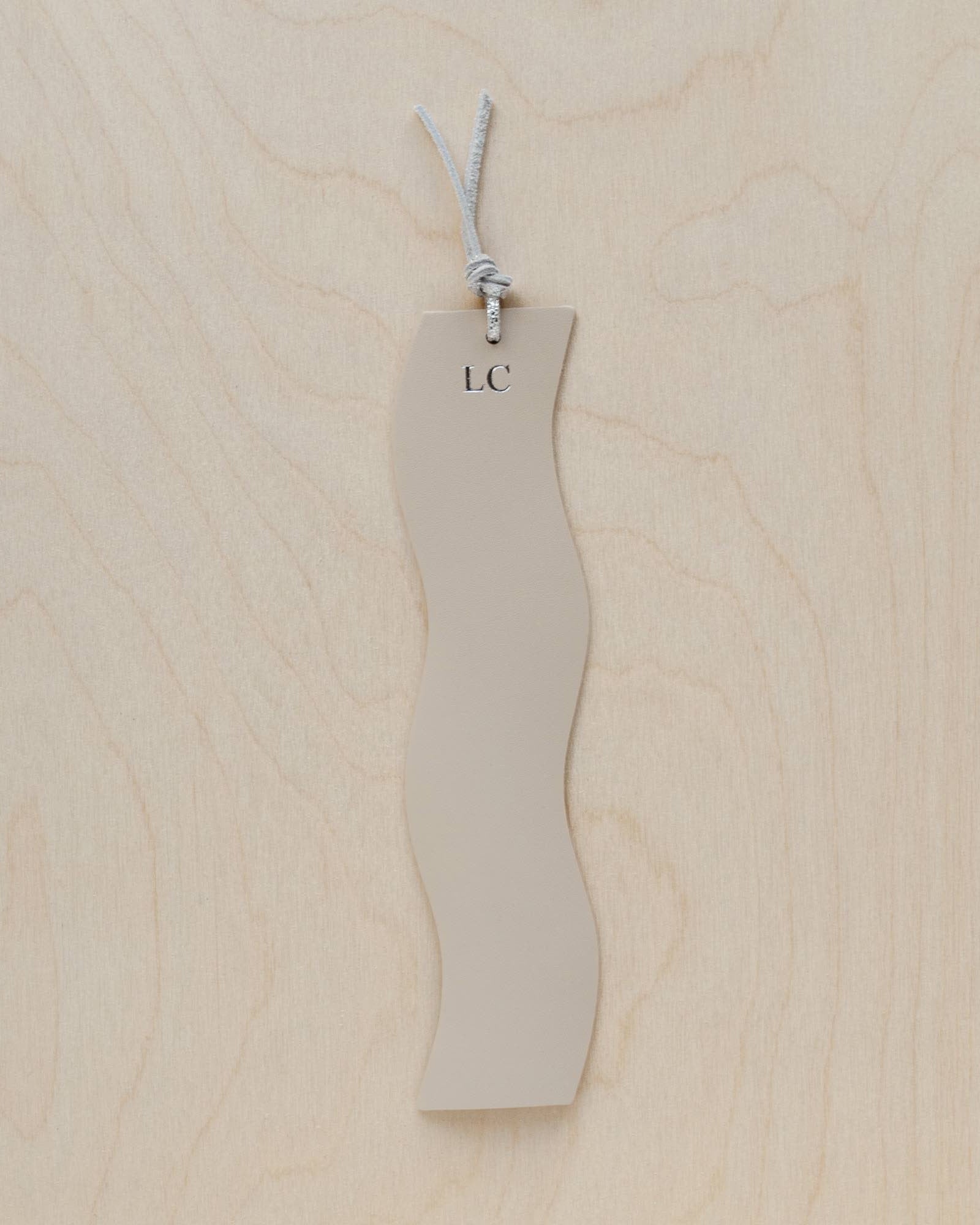 Ivory leather booksmark on a wooden background.