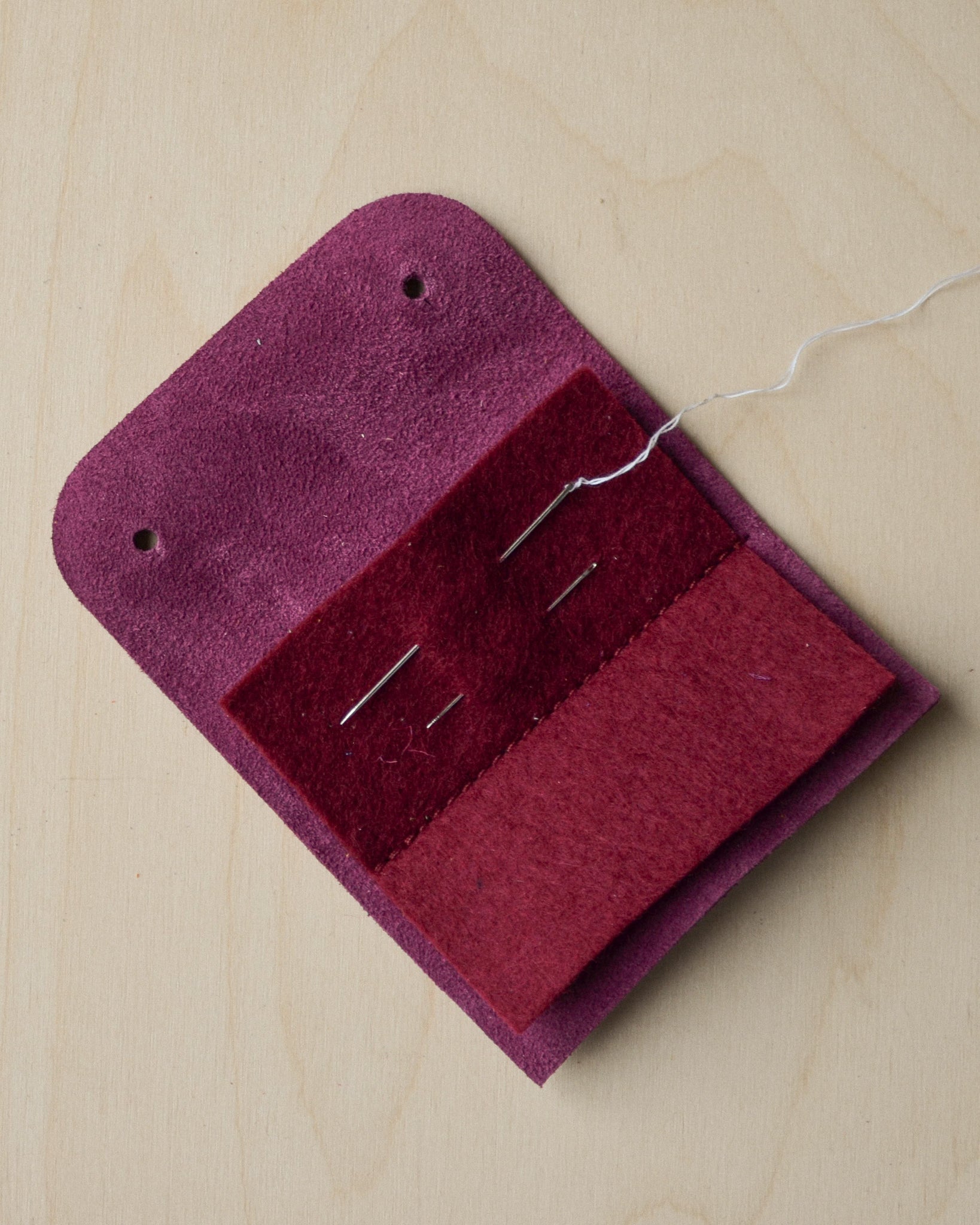 Open Plum purple sewing needle case with needles and thread.