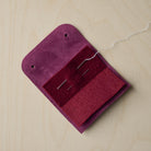 Open Plum purple sewing needle case with needles and thread.