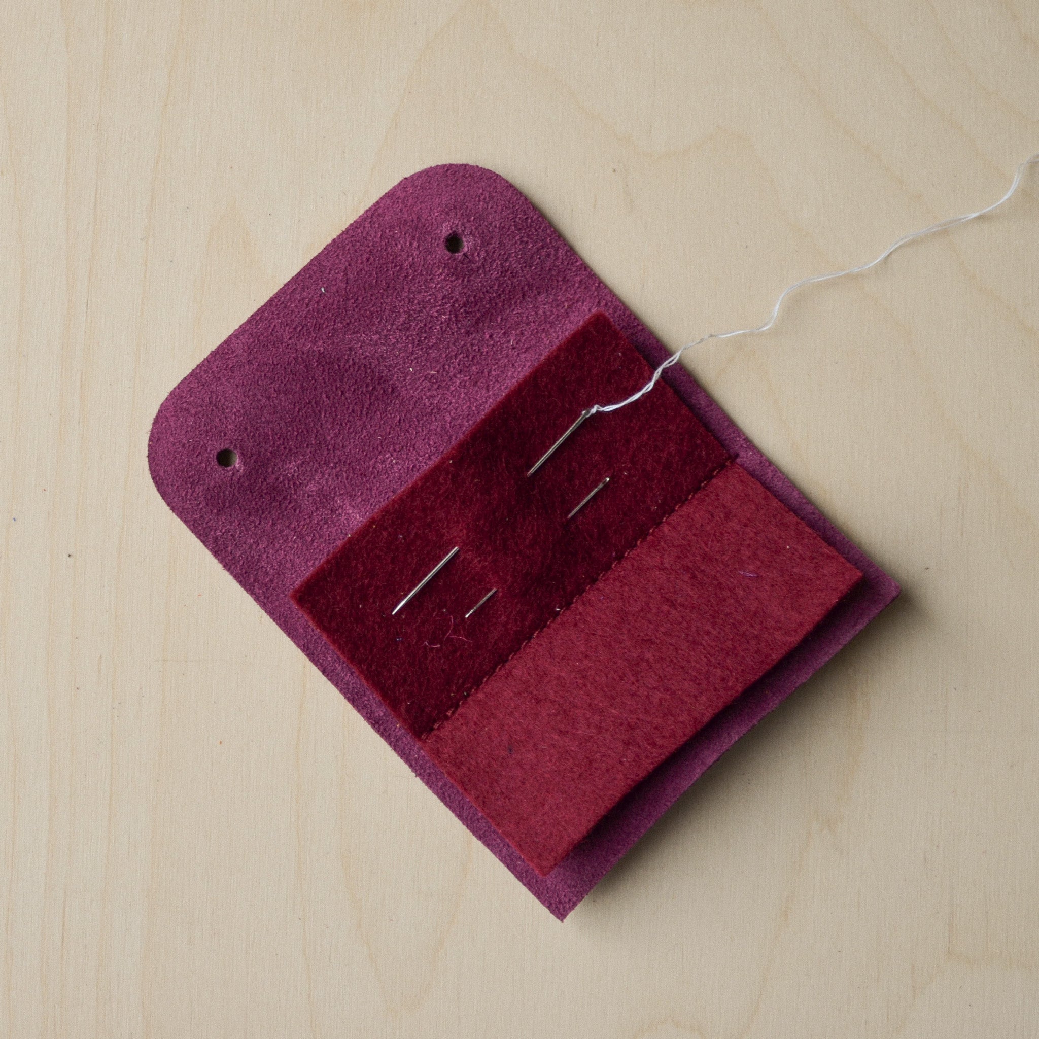Open Plum purple sewing needle case with needles and thread.