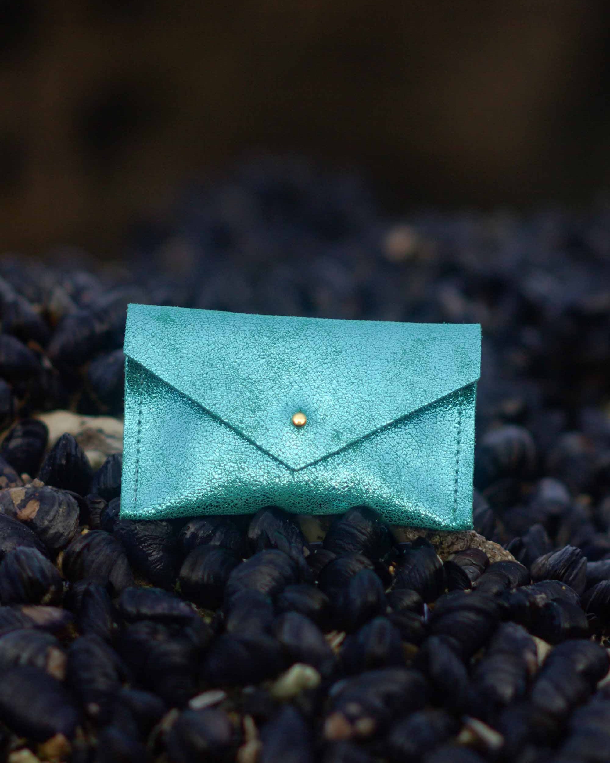Turquoise leather envelope wallet on a textured black surface