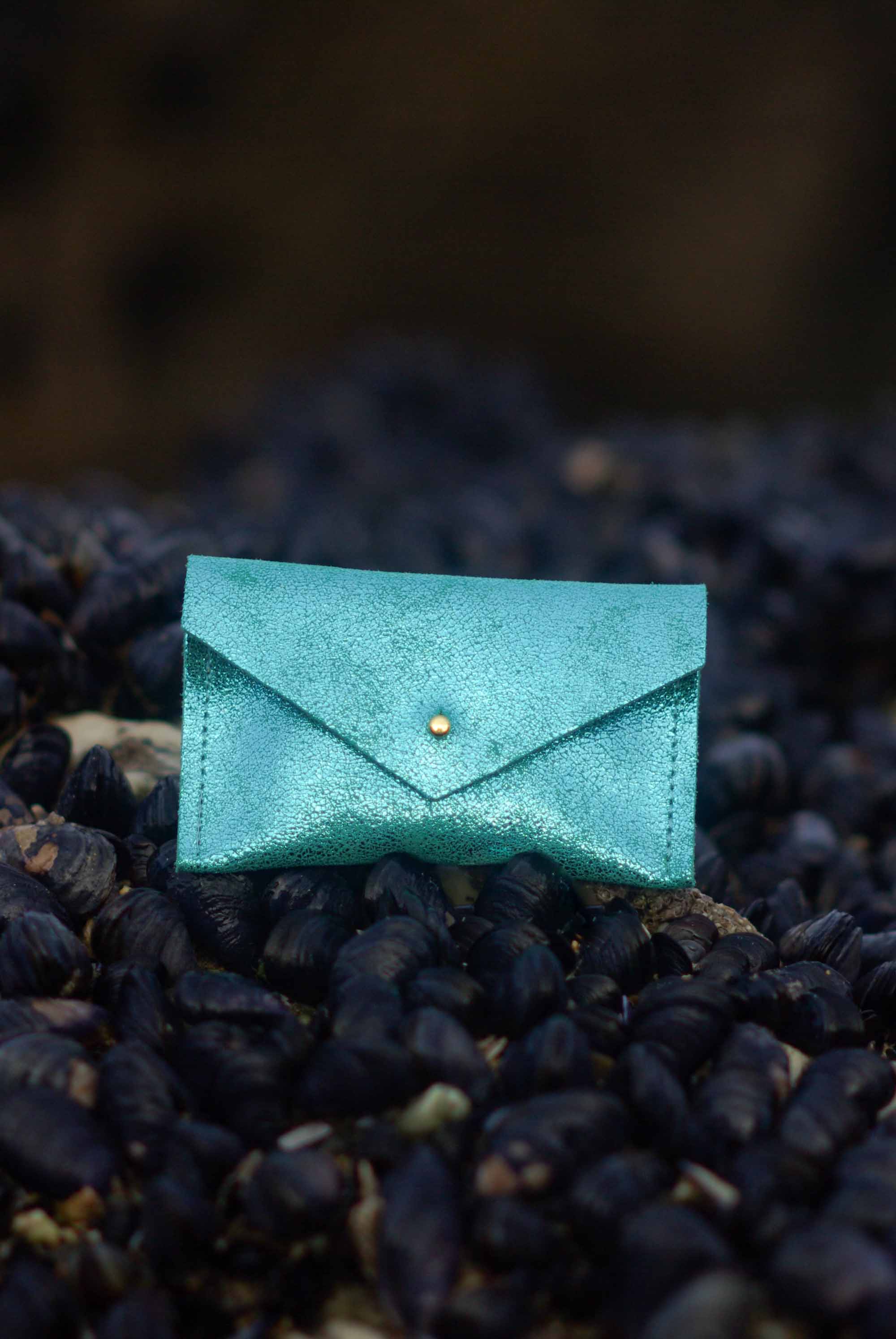 Turquoise leather envelope wallet on a textured black surface