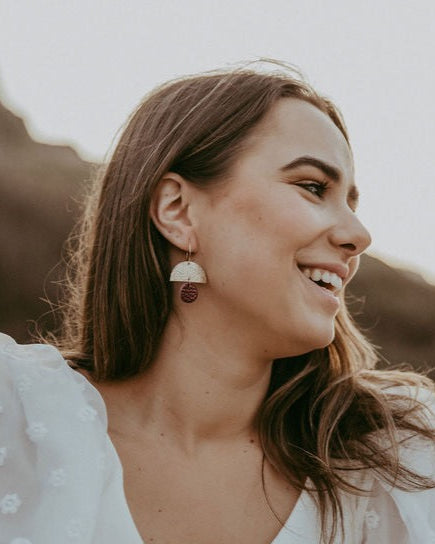 Burgundy and gold statement earrings worn by a women at a boho wedding.