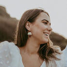 Burgundy and gold statement earrings worn by a women at a boho wedding.
