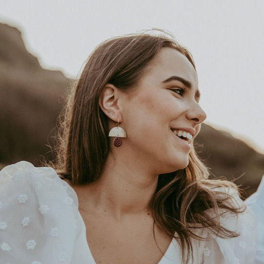Burgundy and gold statement earrings worn by a women at a boho wedding.