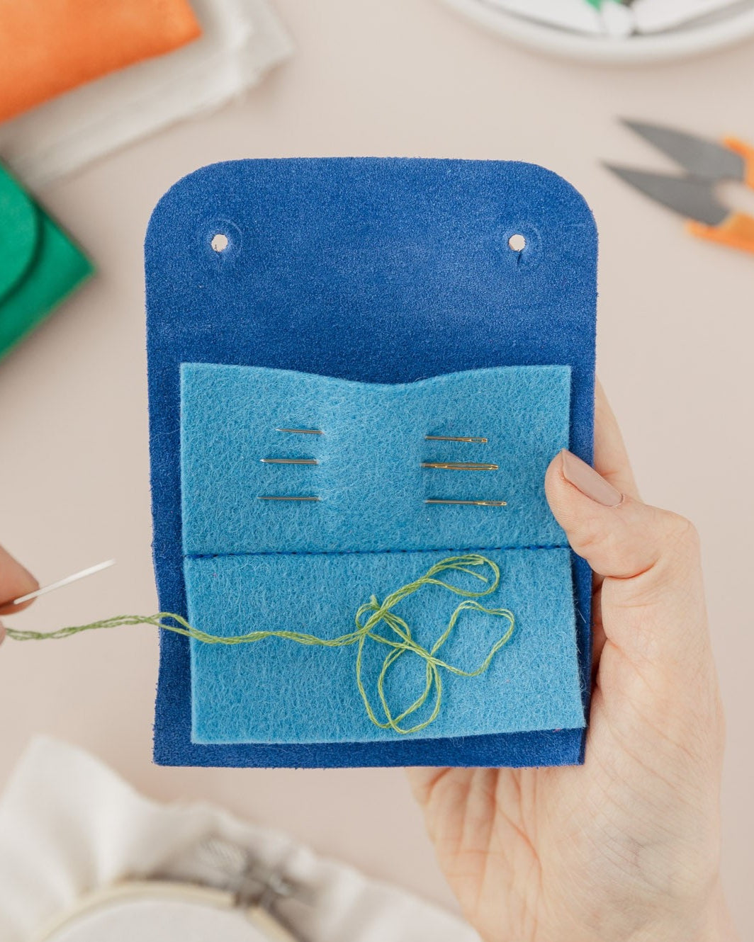 Action shot of the sewing needle case in use, featuring needle and thread.
