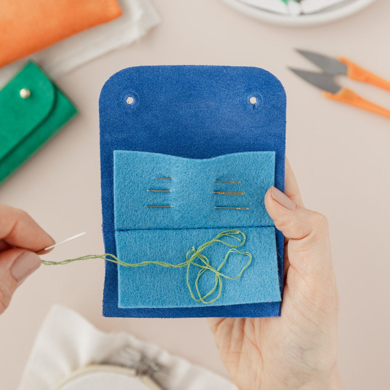 Action shot of the sewing needle case in use, featuring needle and thread.