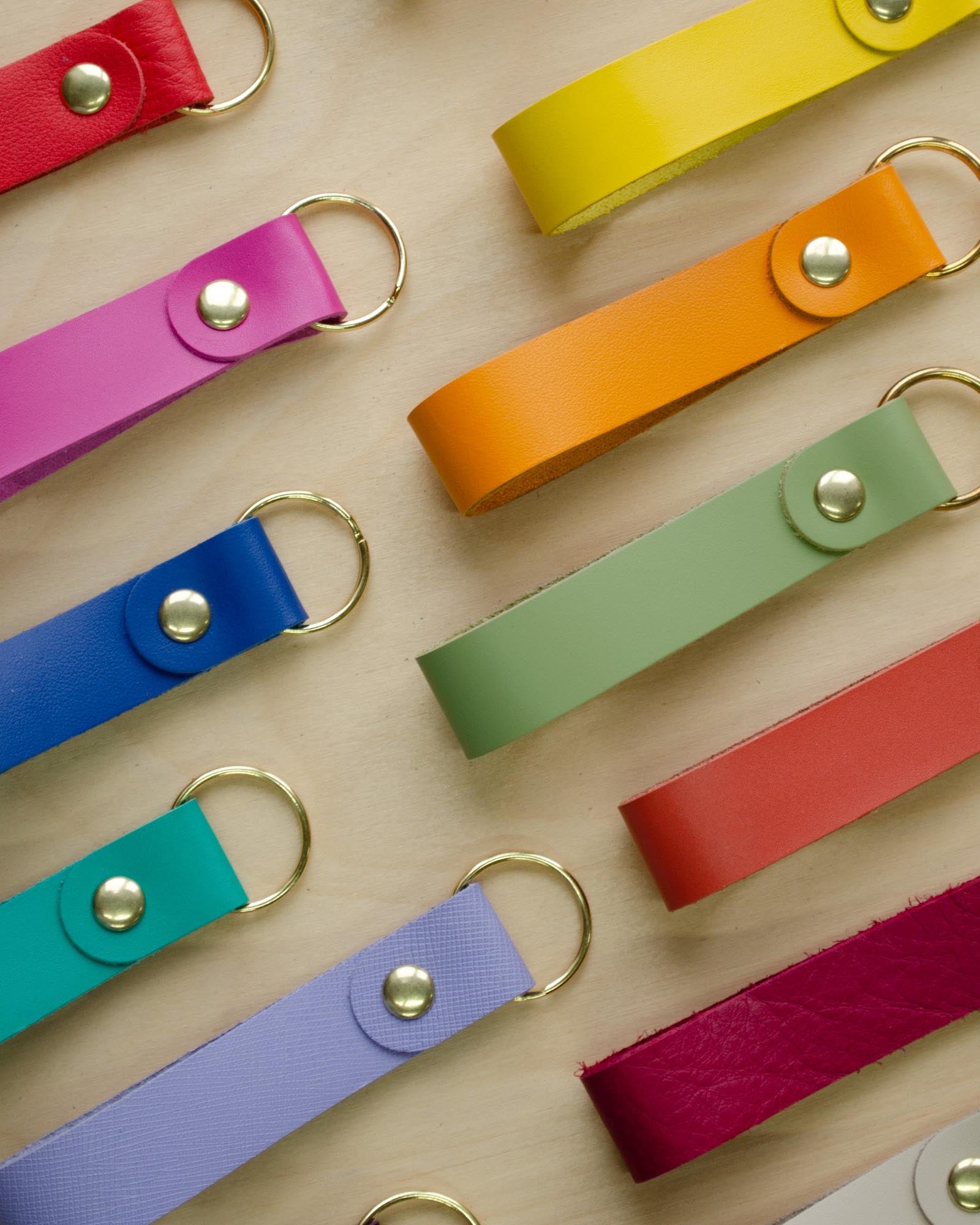 Colourful leather keyrings on a wooden background.