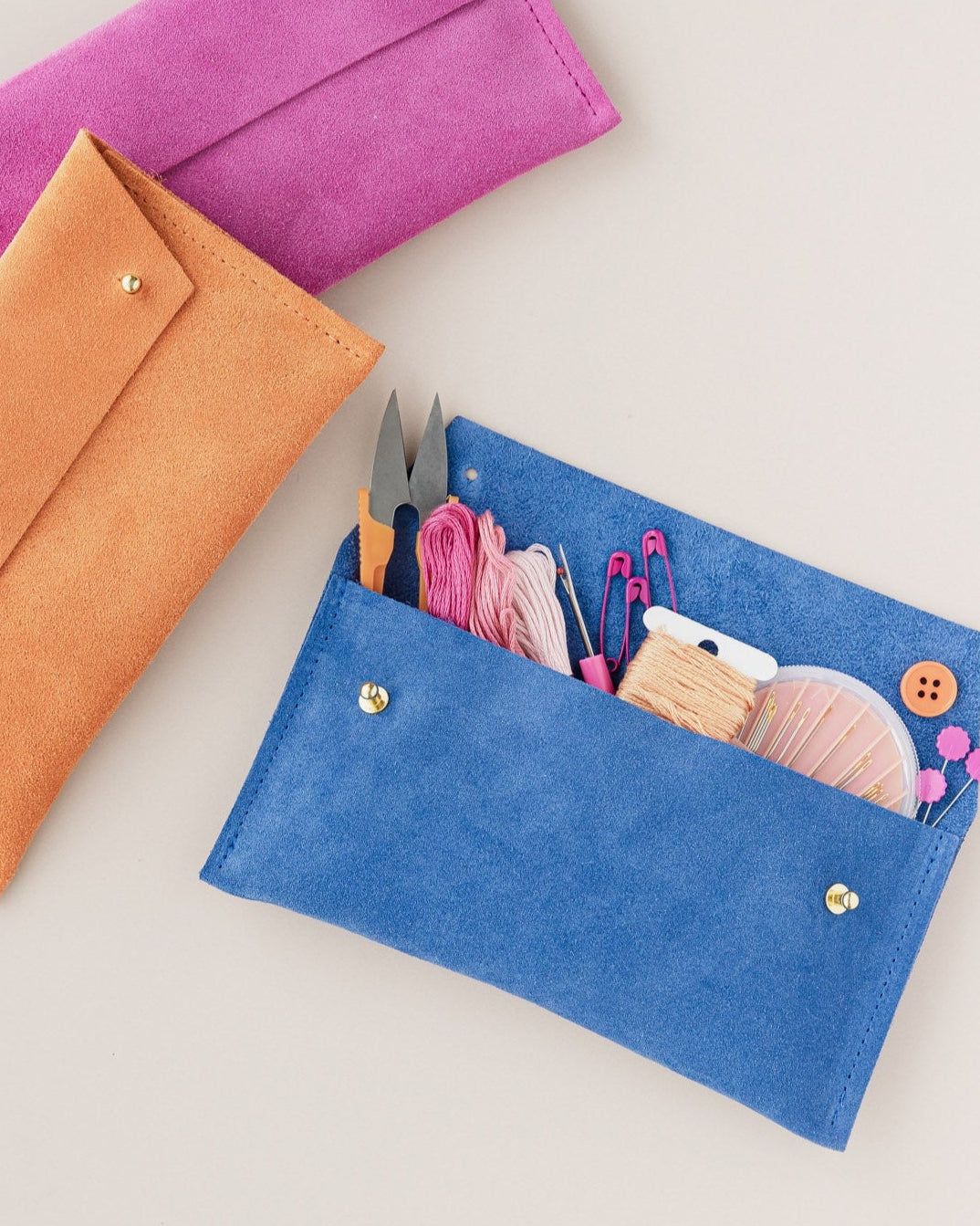 A selection of suede Notions Pouches in Fuchsia, Orange and Cobalt. Full with sewing notions.