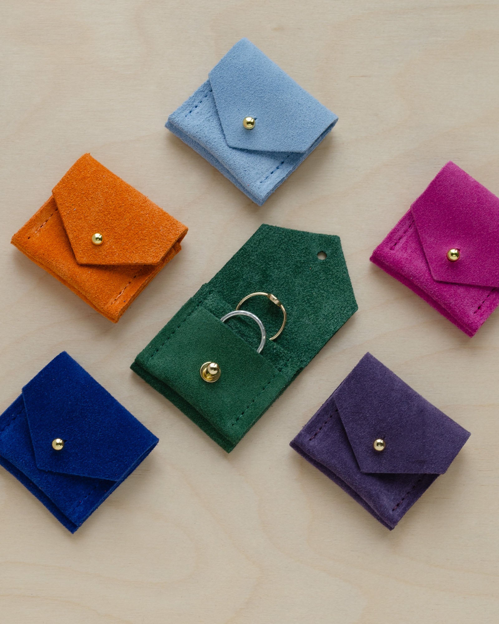 Six wedding ring pouches from the suede colour range. Featuring, Pale Blue, Clementine Orange, Fuchsia Pink, Moss Green, Ultramarine Blue and Grape Purple.