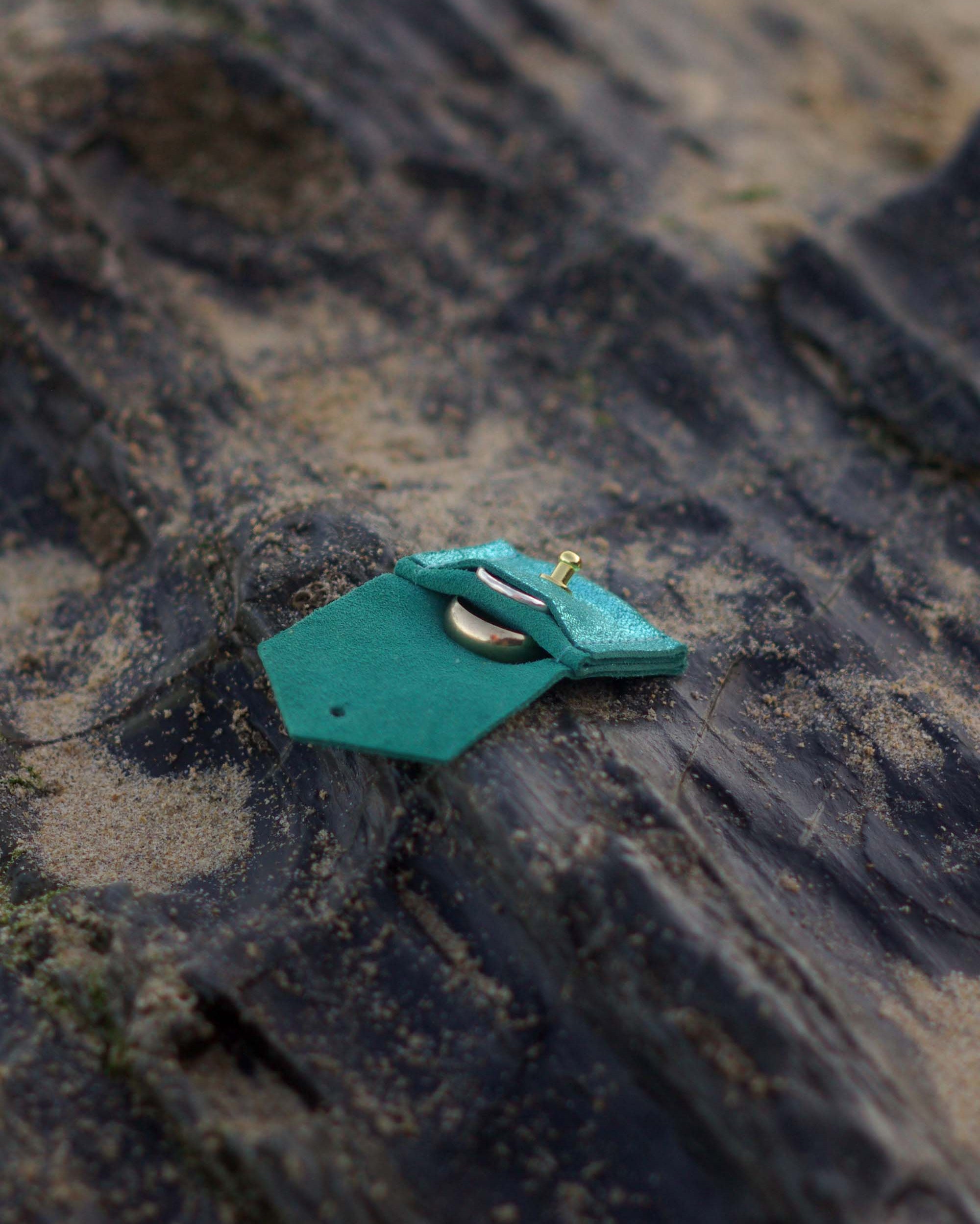 Turquoise leather wedding ring pouch with on a textured surface