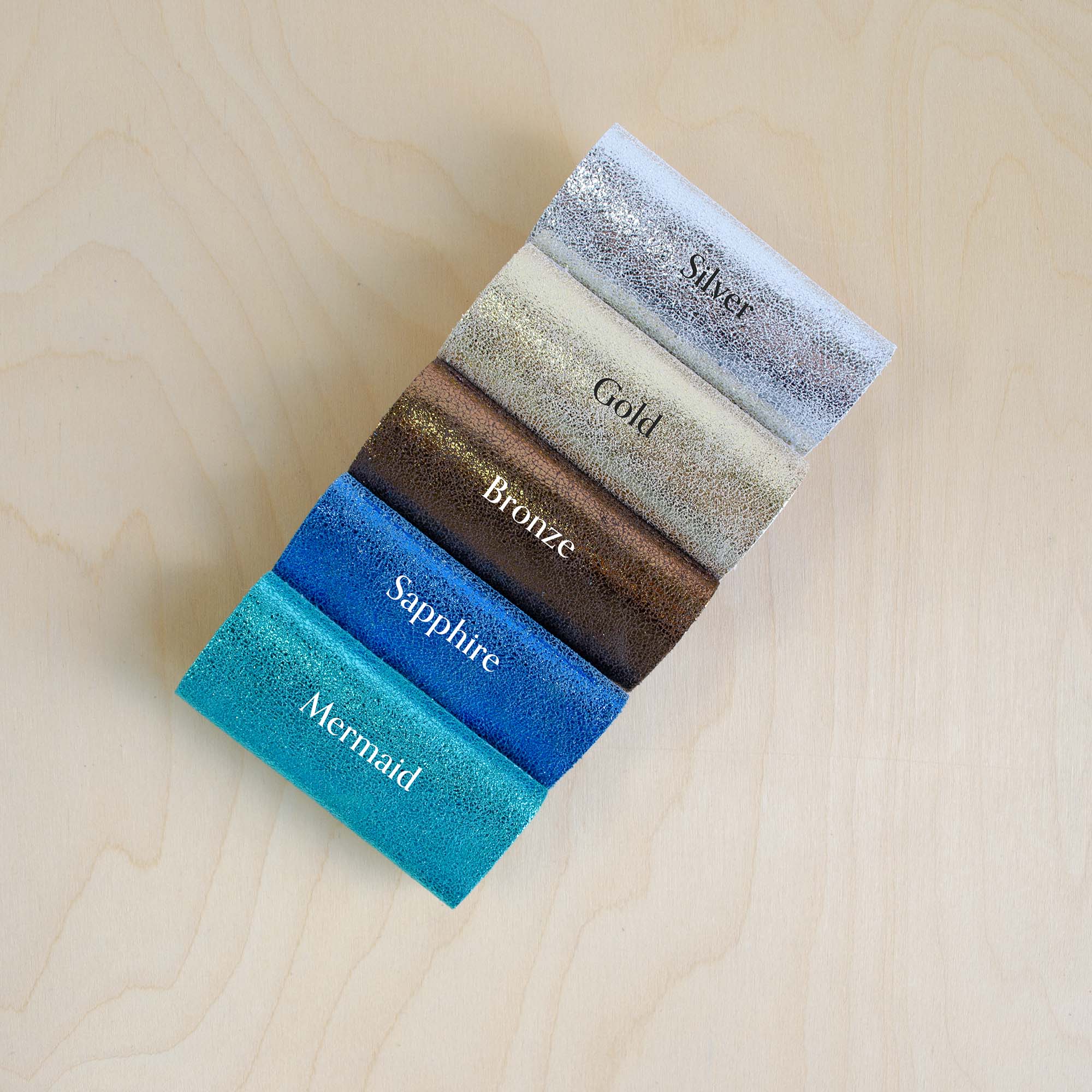 Color swatch samples labeled 'Silver', 'Gold', 'Bronze', 'Sapphire', and 'Mermaid' on a wooden surface.