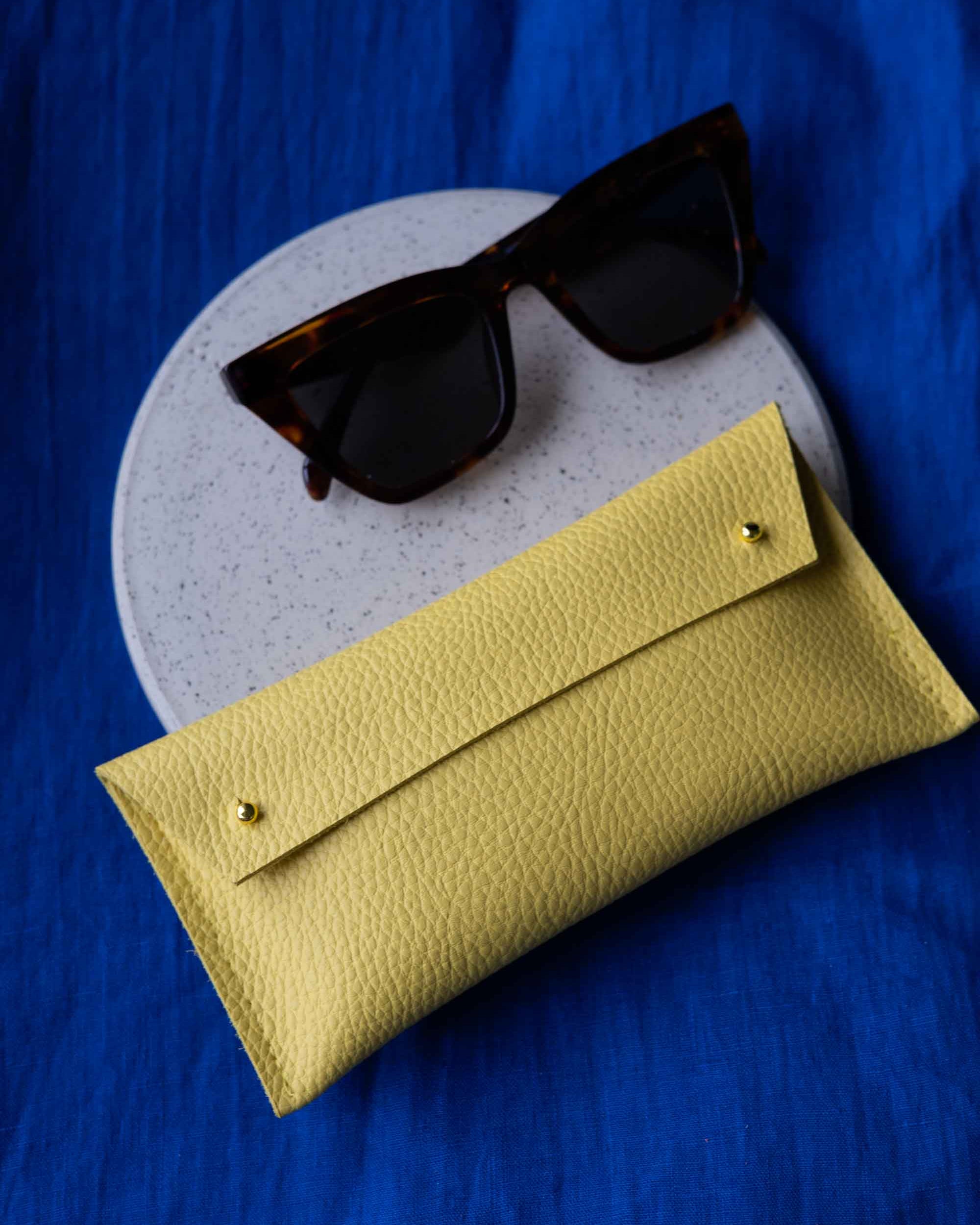 Yellow sunglasses case with sunglasses on a blue background