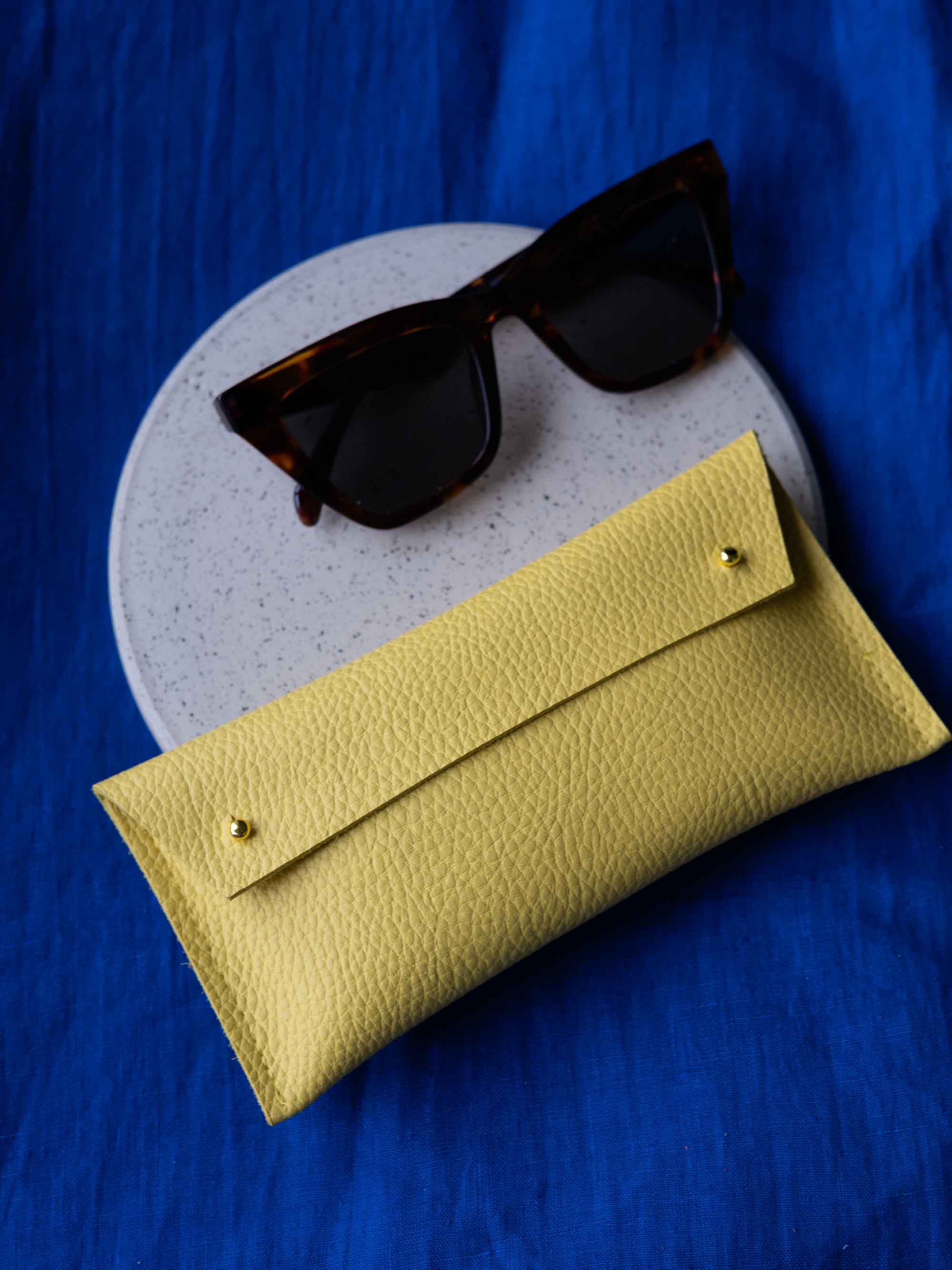 Yellow sunglasses case with sunglasses on a blue background