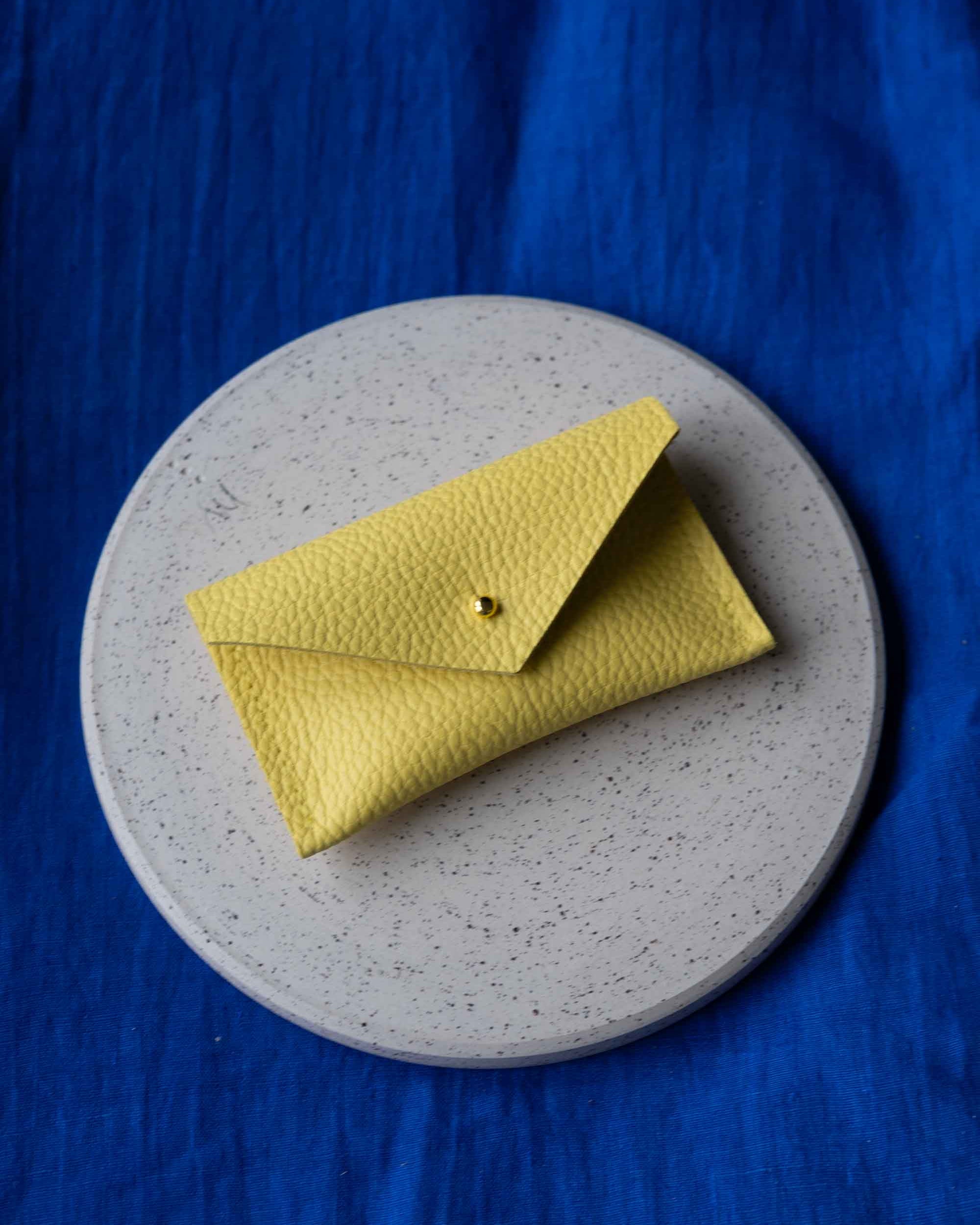 Yellow wallet on a gray plate with a blue background
