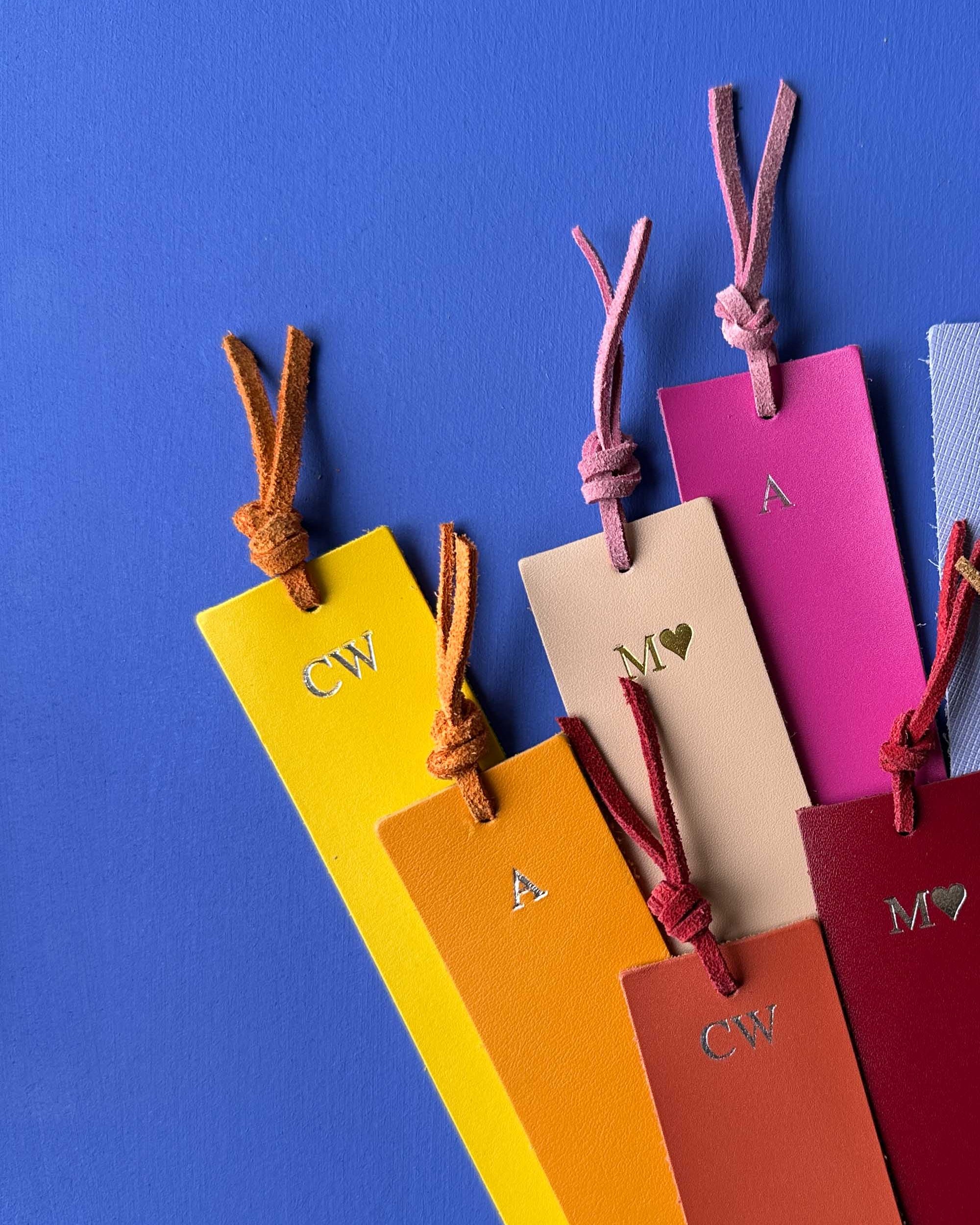 Colorful leather bookmarks with initials on a blue background