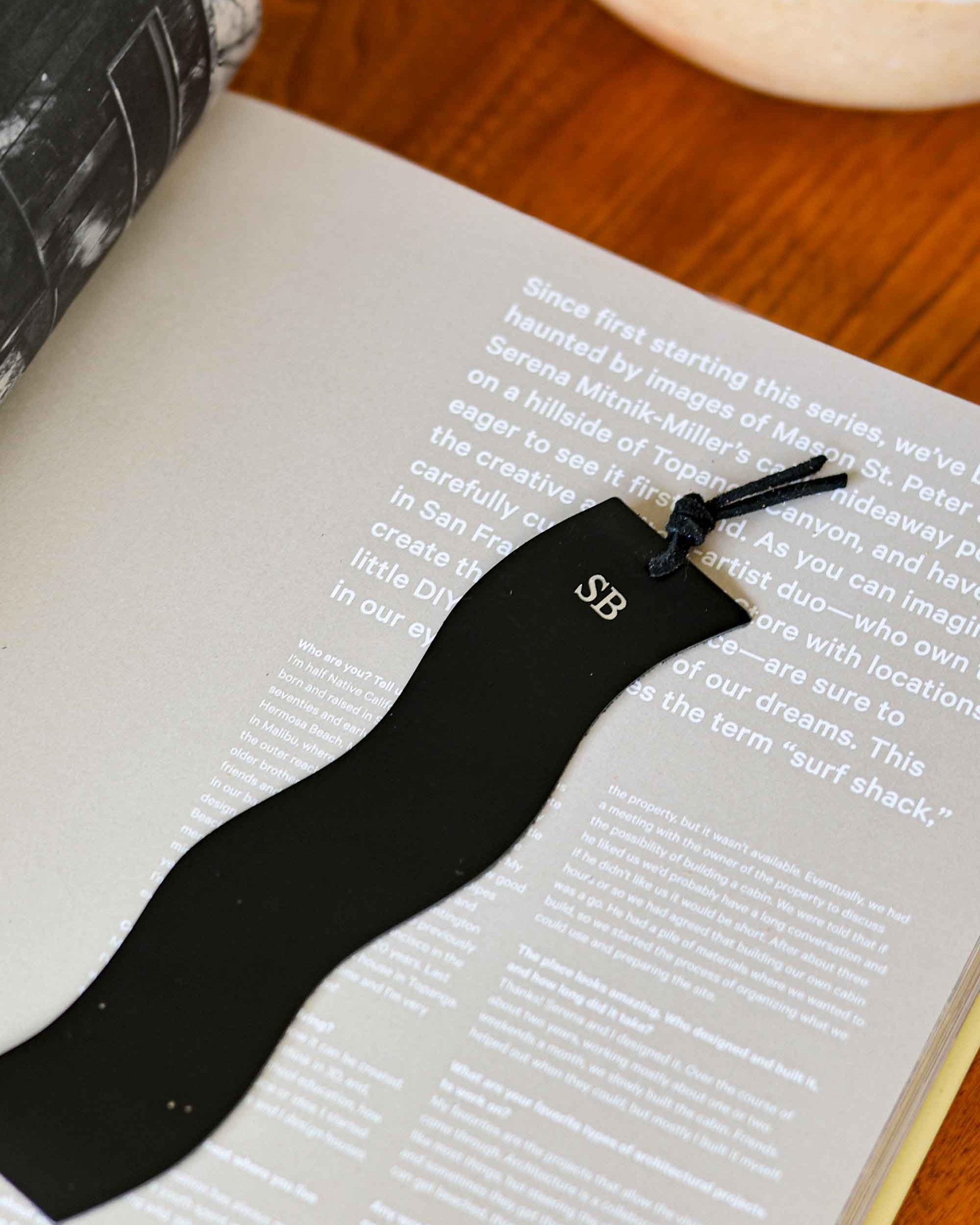Black wavy shape bookmark with initials on a book