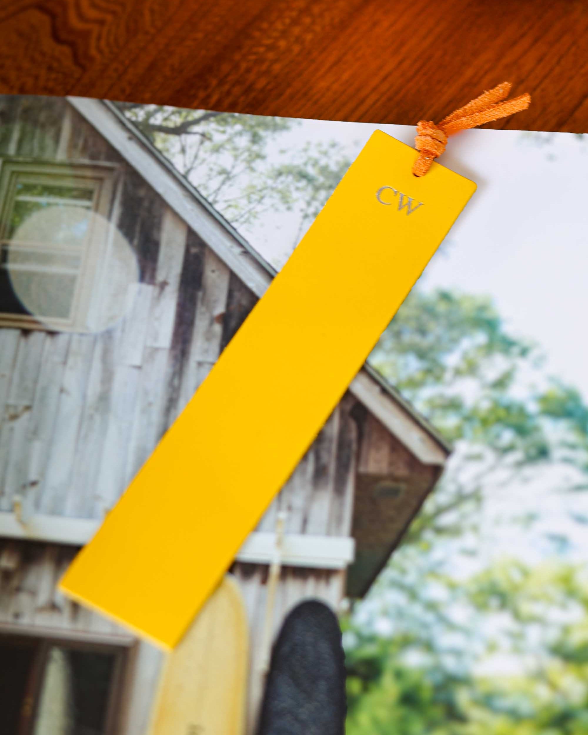 Yellow bookmark with 'CW' branding on a photo of a house and trees
