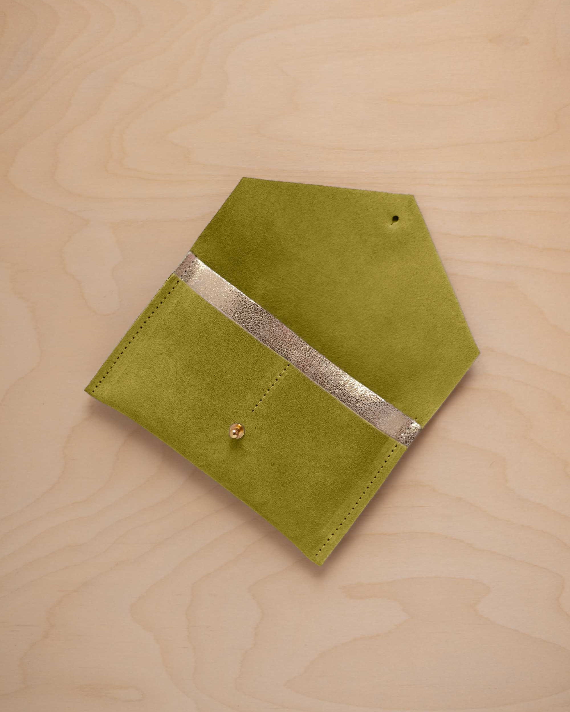 A chartreuse lime green coloured suede pouch with a metallic gold contrast pocket and a small gold stud, displayed on a light wood grain background.