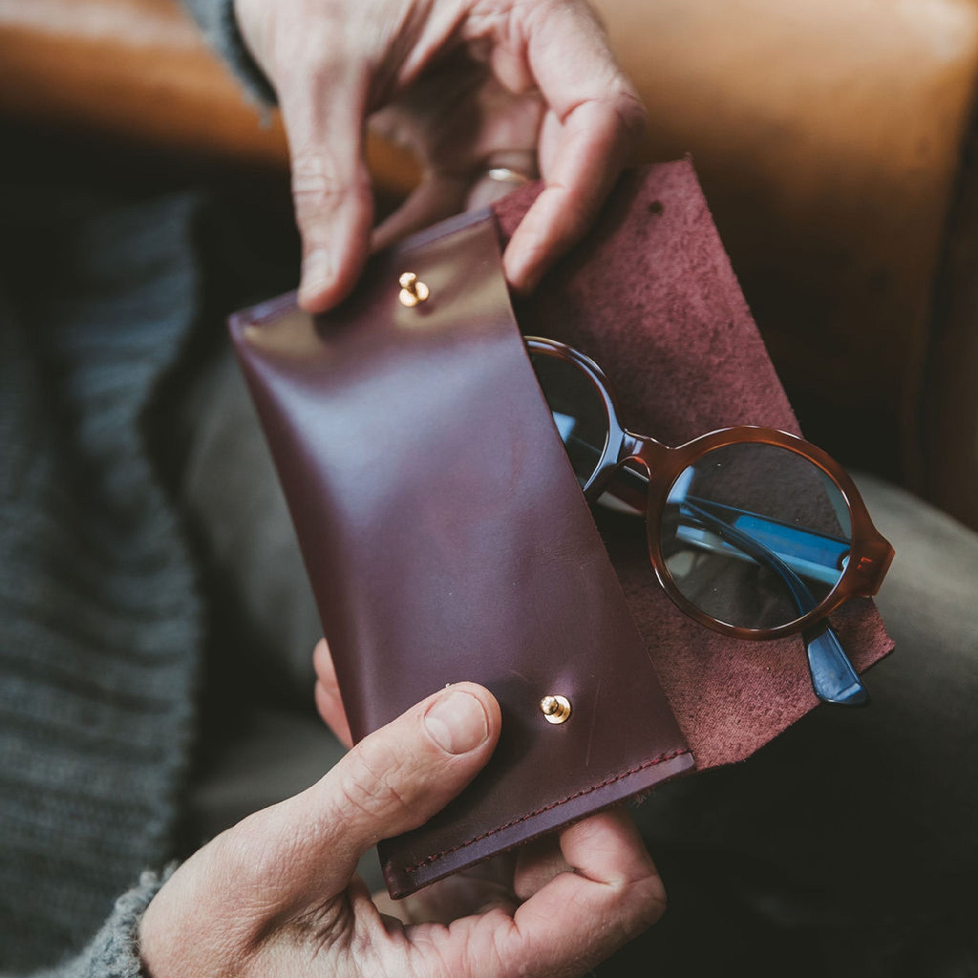 Brown leather glasses case open with a pair of brown sunglasses inside.