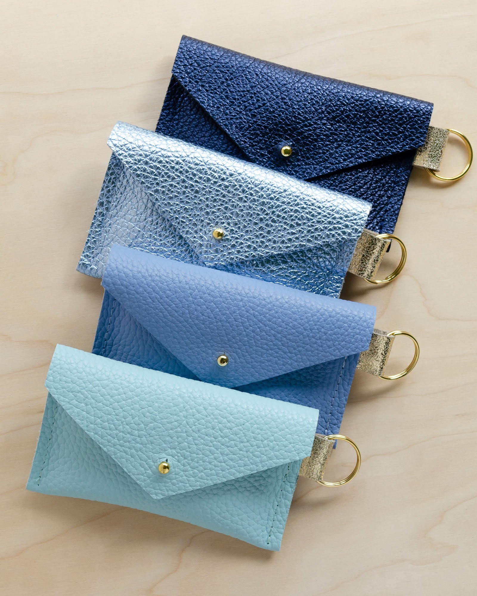 Four of the leather keyring card holders in Metallic Navy, Metallic Diamond, Powder Blue and Seaglass.
